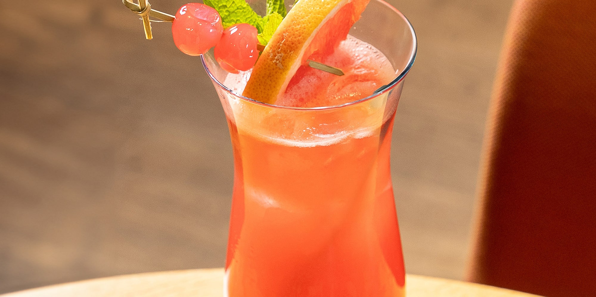 a glass of pink drink with fruit and mint