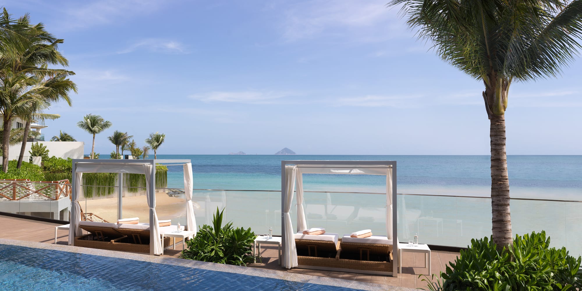 a pool with lounge chairs and a beach in the background
