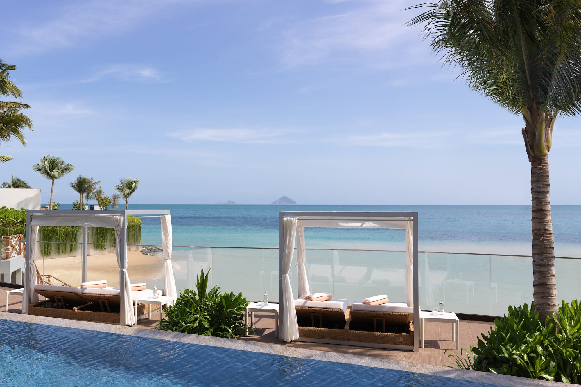 a pool with lounge chairs and a beach in the background