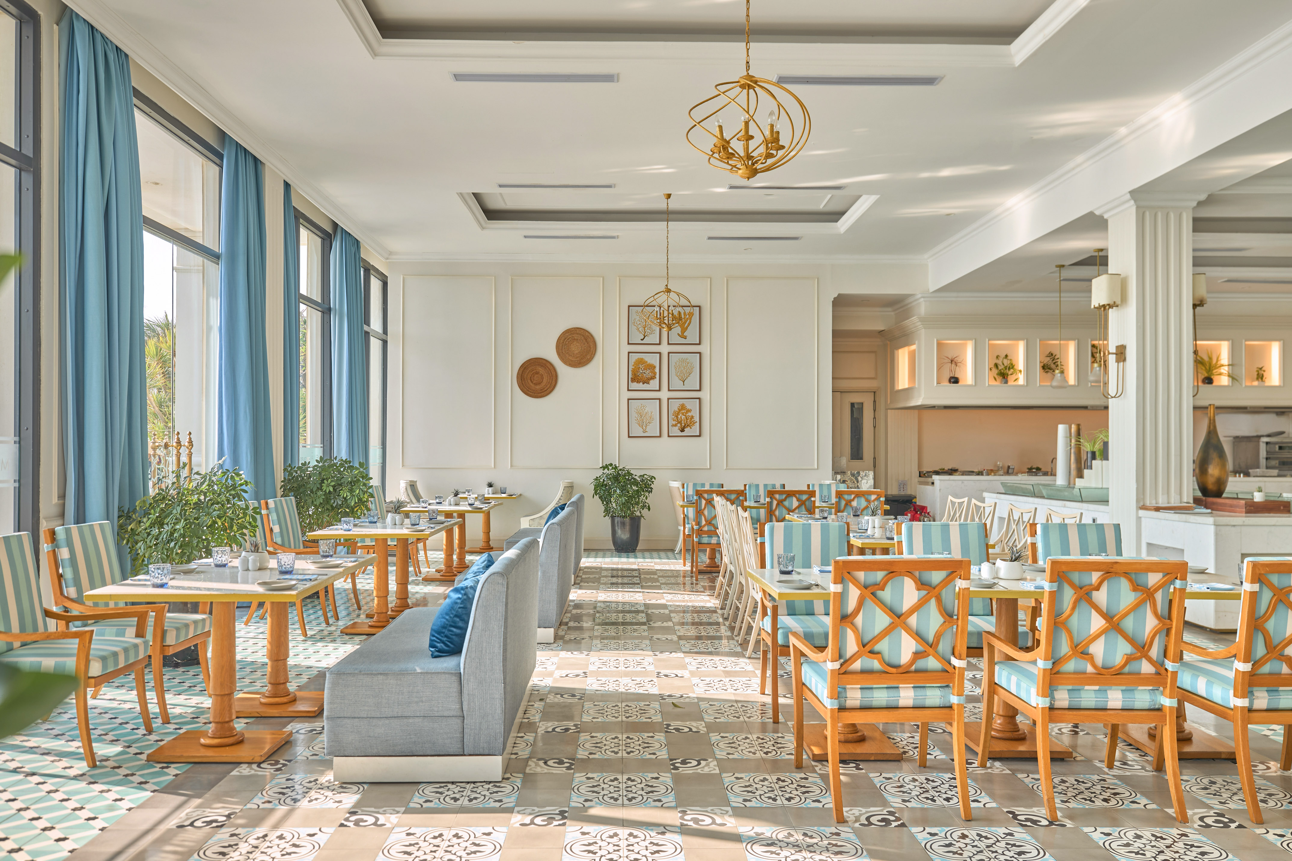 Elegant coastal restaurant interior with blue and white decor and chandeliers.