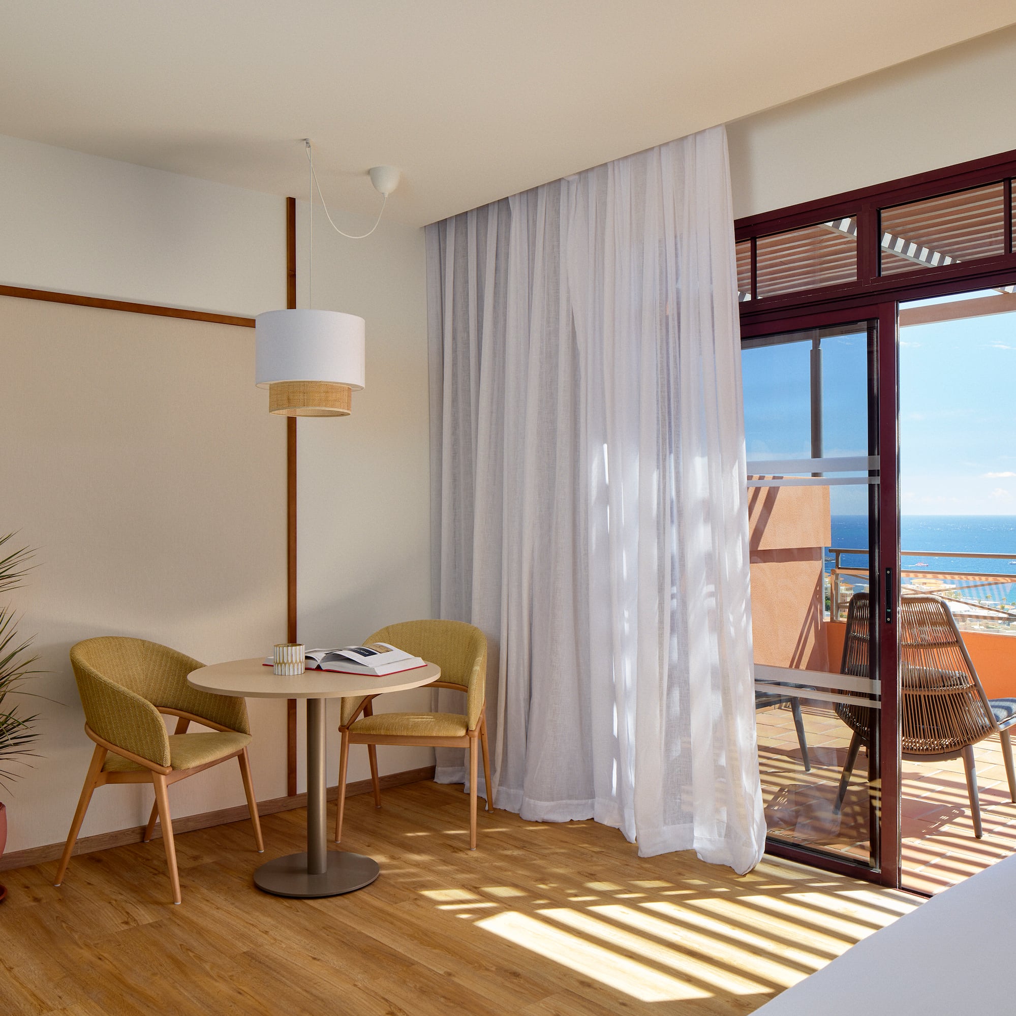 a room with a table and chairs and a balcony overlooking the ocean