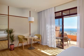 a room with a table and chairs and a balcony overlooking the ocean