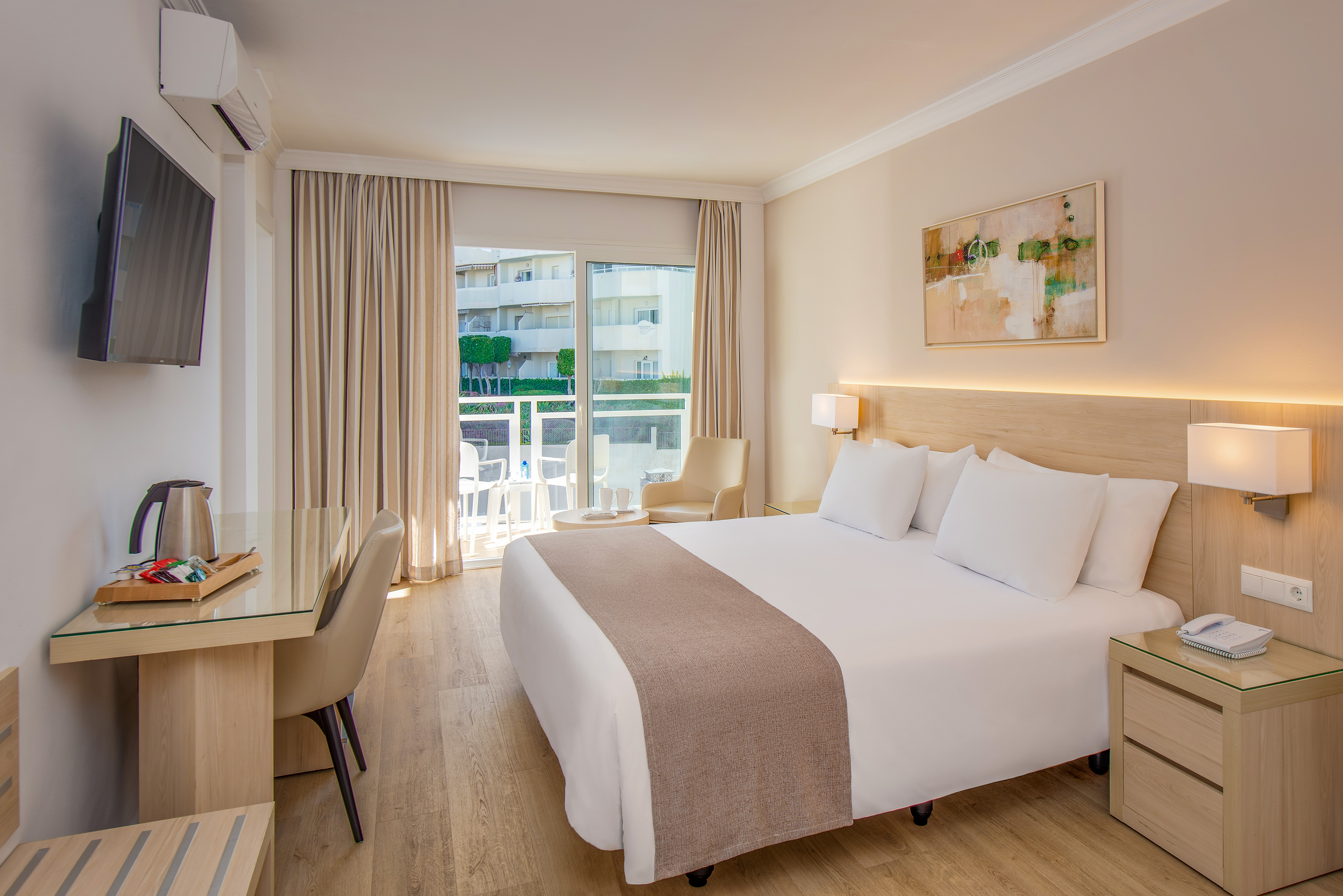 Bright hotel room with comfortable bed, balcony, and modern amenities.