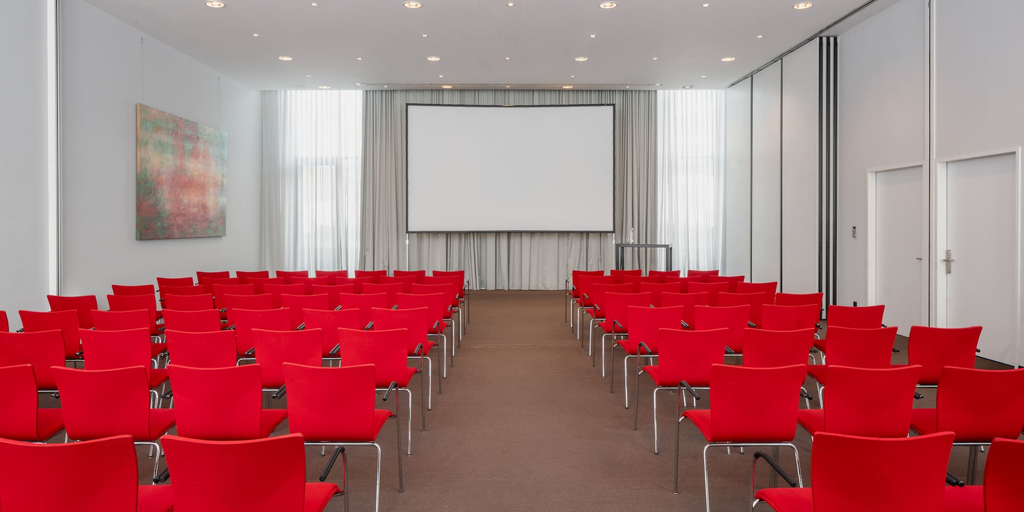 a room with red chairs and a projector screen