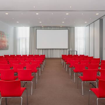a room with red chairs and a projector screen