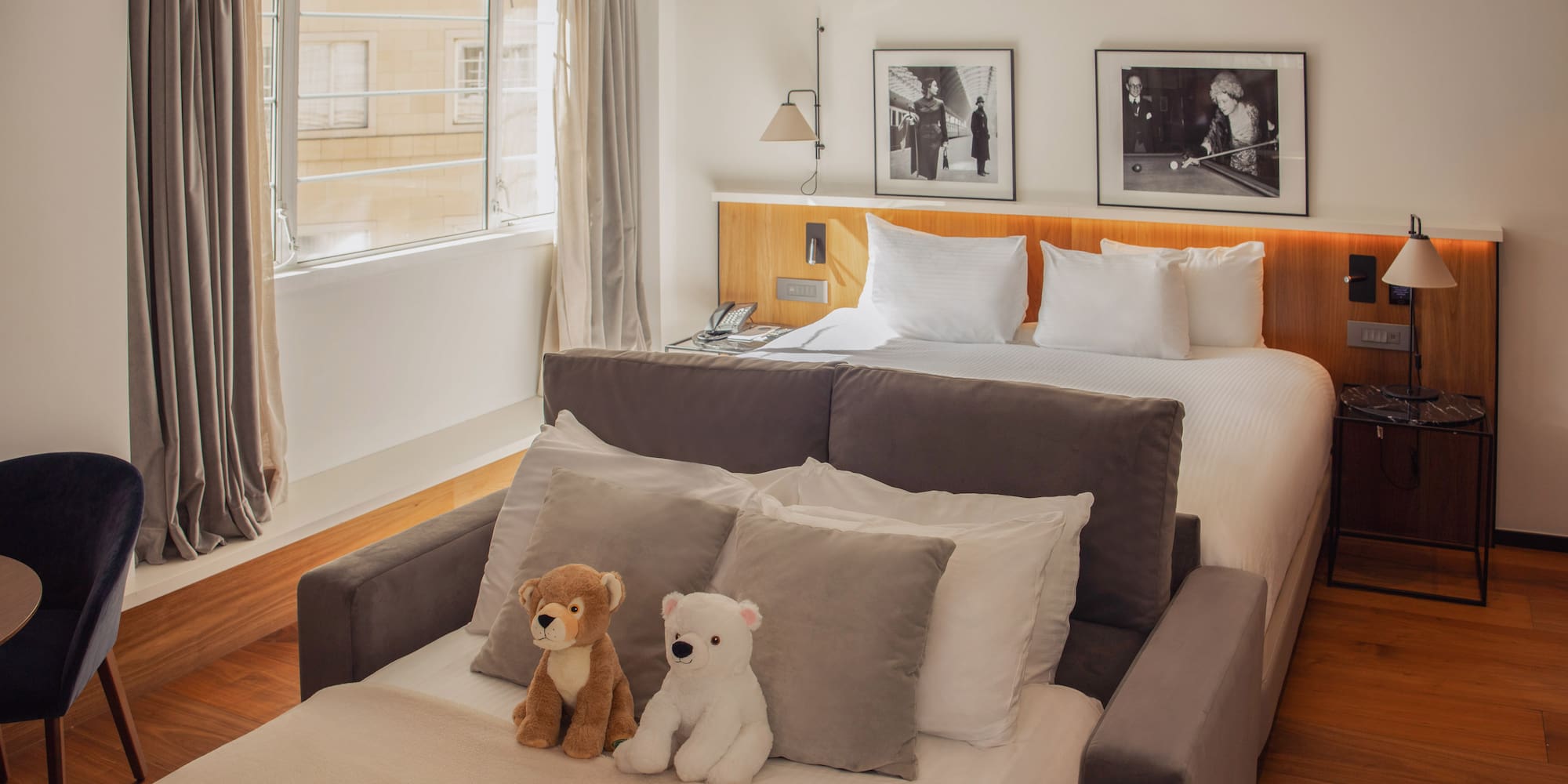 Cozy hotel room with a king bed, sofa bed, and two adorable teddy bears.