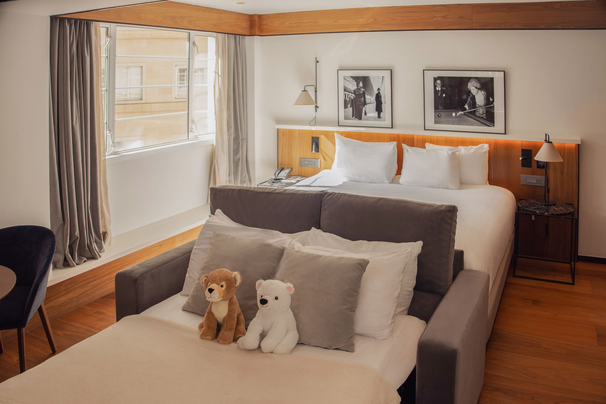 Family hotel room with large bed, sofa bed, and two teddy bears.