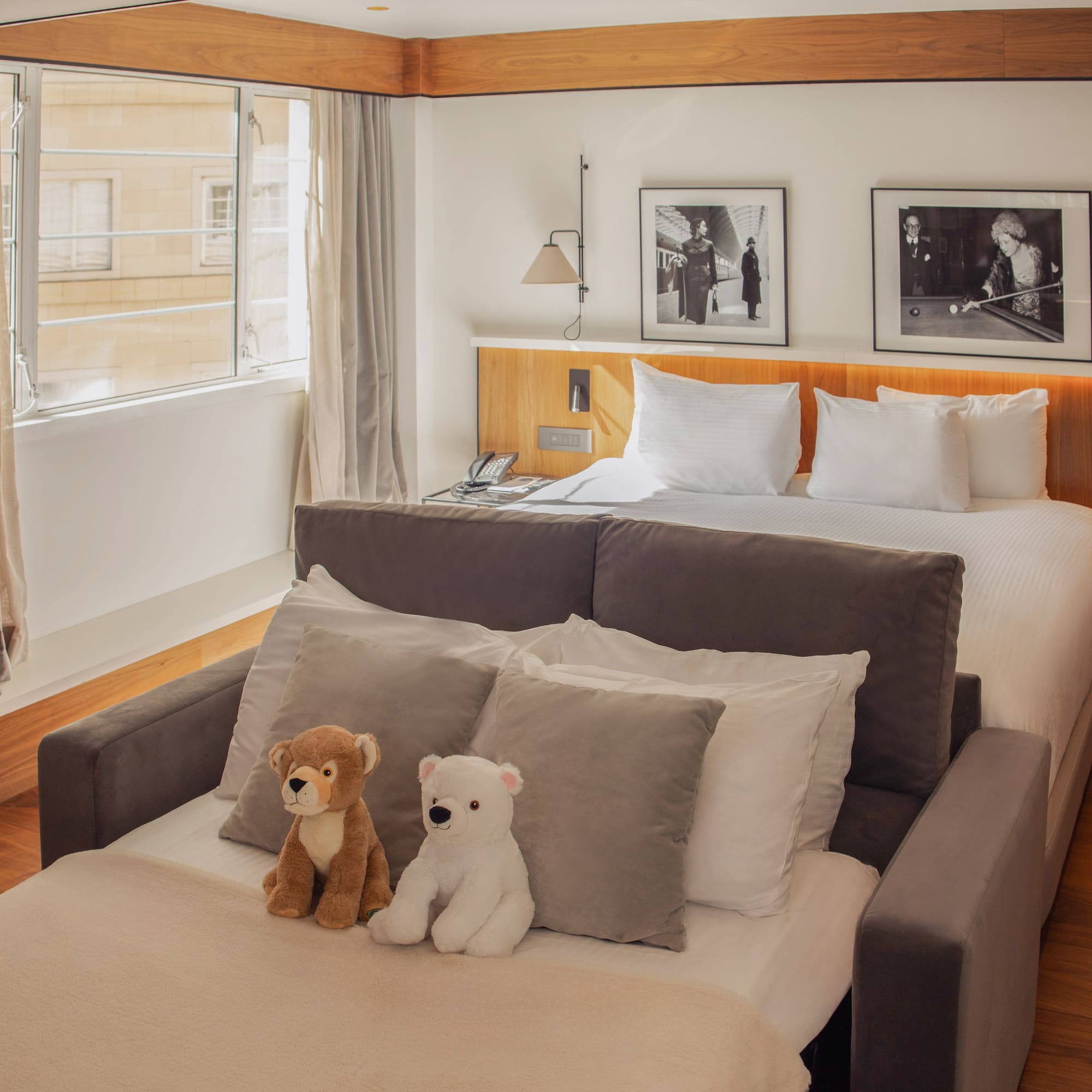 Cozy hotel room with a king bed, sofa bed, and two adorable teddy bears.