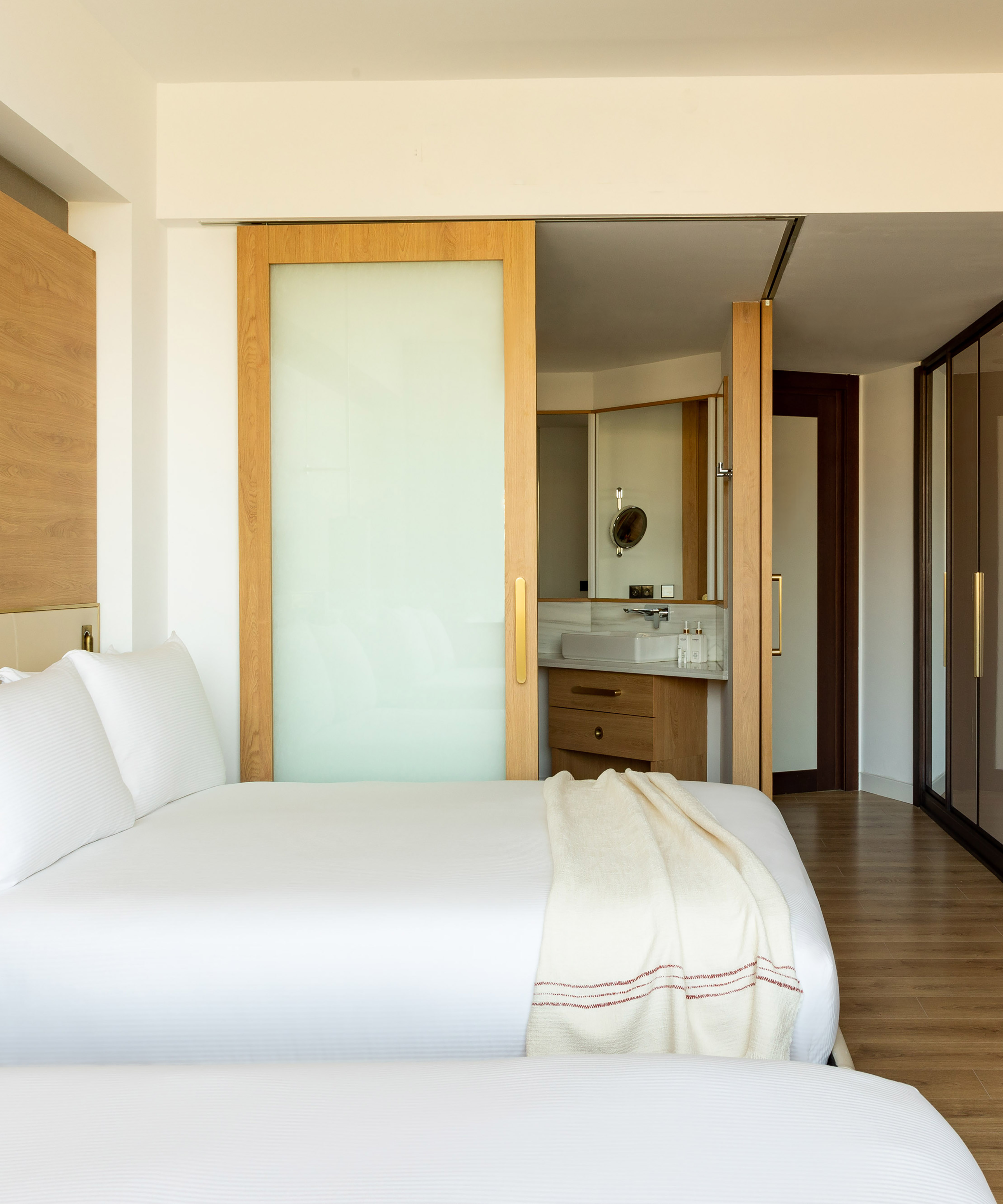 Clean modern hotel bedroom with white bed and sliding door to bathroom.