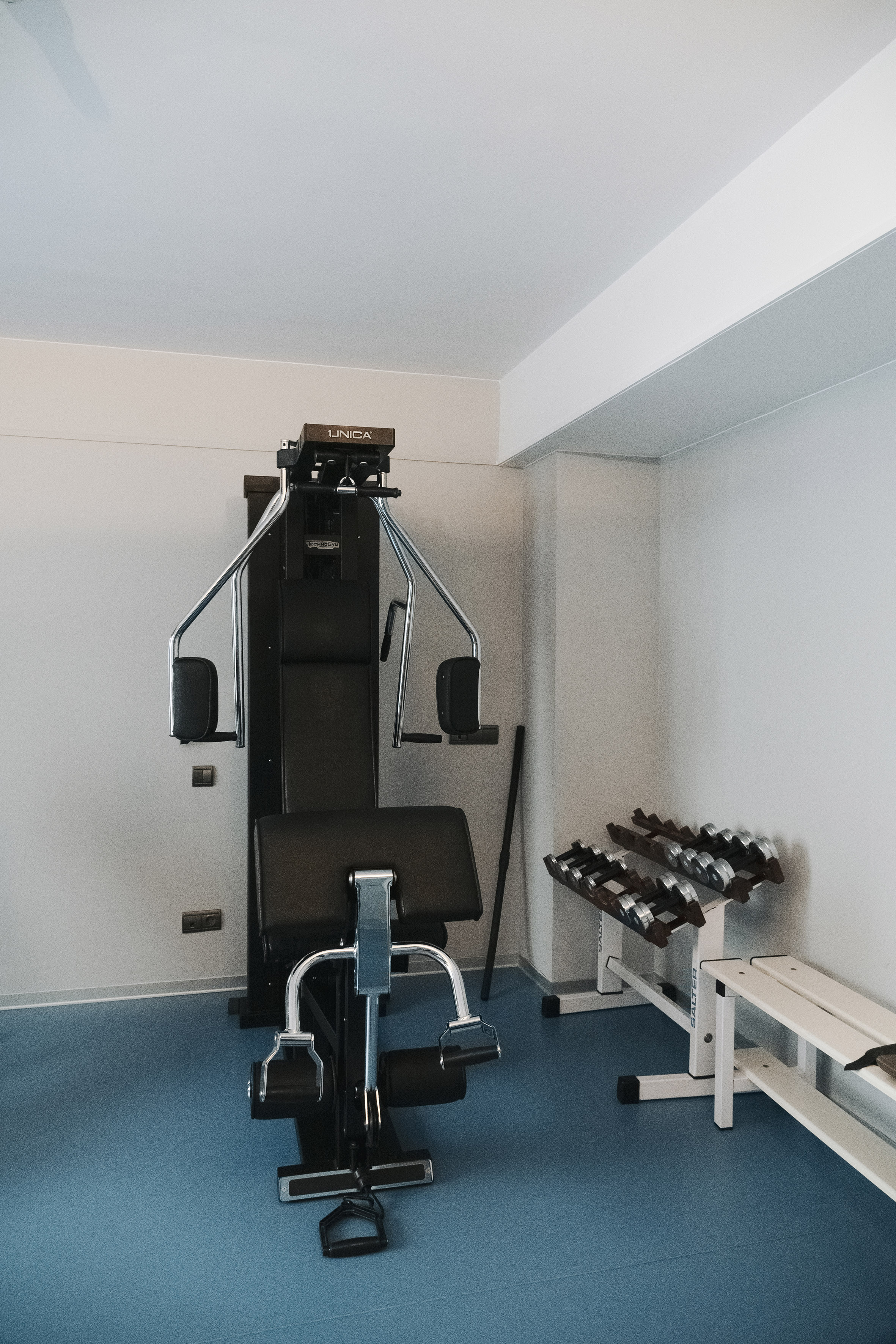 Technogym multi-gym machine, dumbbells, and bench in a clean fitness room. - Sală de sport - Palacio de Avilés Afiliat Meliá, Avilés