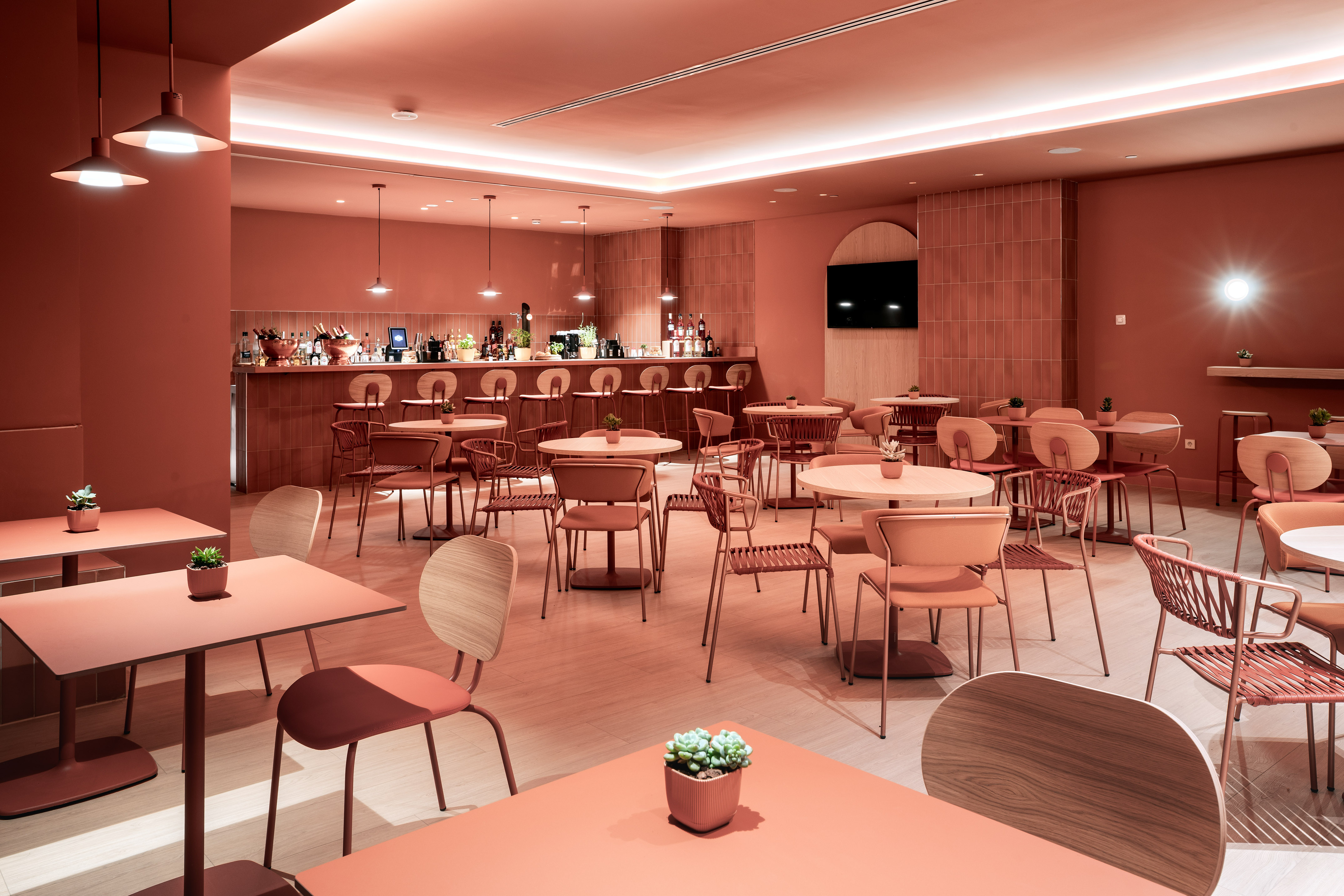 Modern coral cafe interior with bar, dining tables, and seating.
