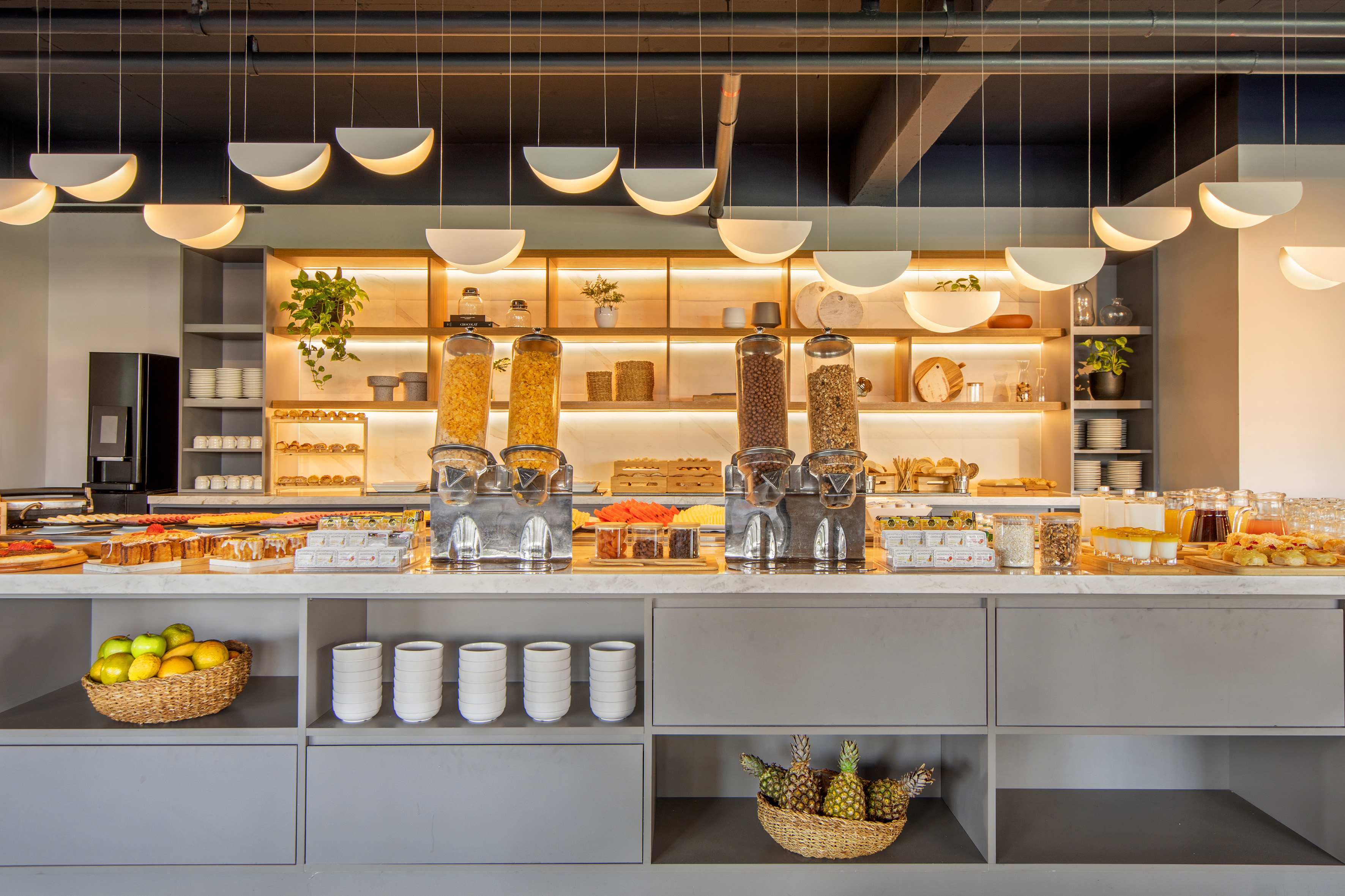 Modern hotel breakfast buffet with cereal, pastries, fresh fruit, and juices.