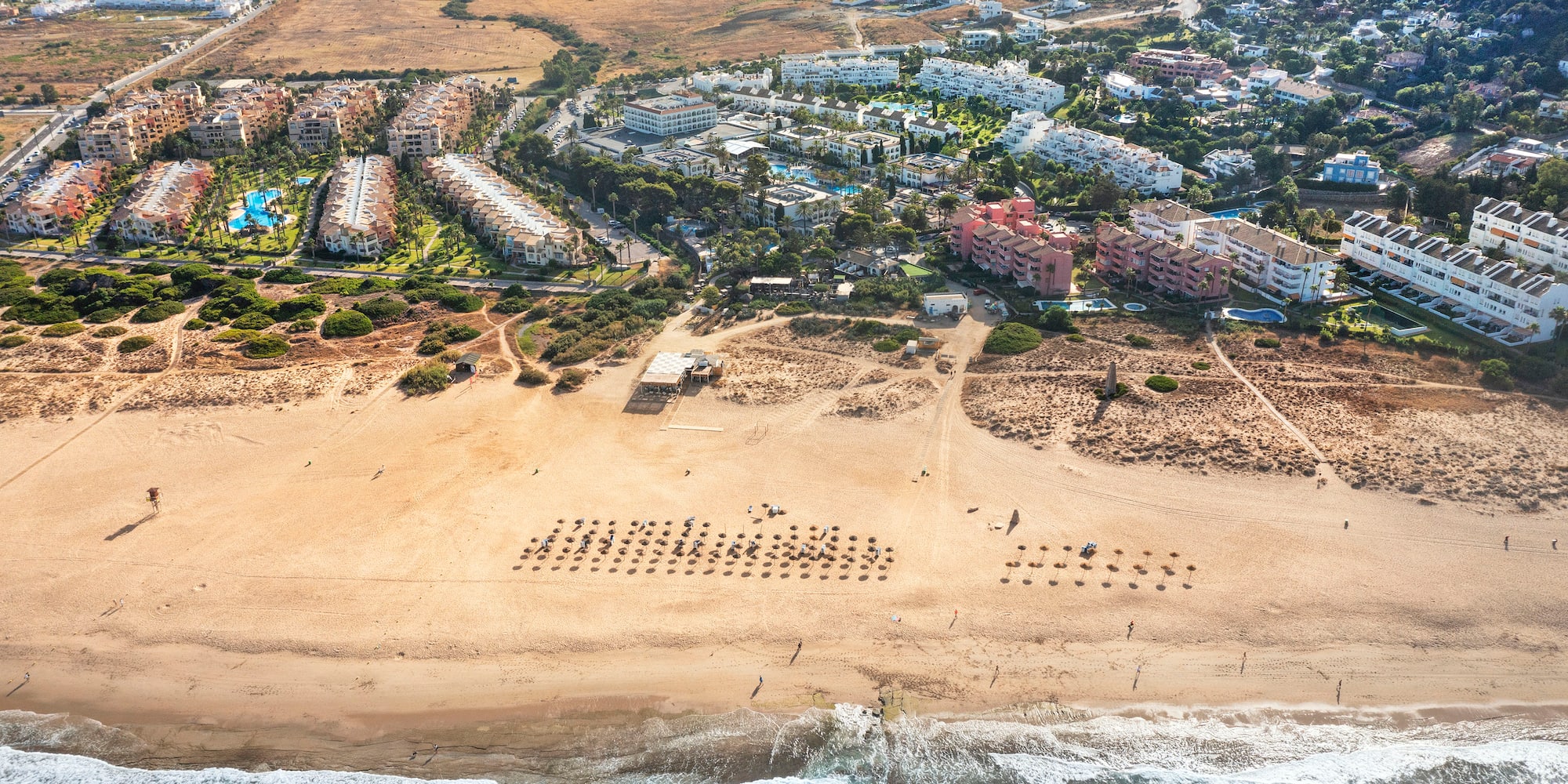 an aerial view of a beach with buildings and a body of water