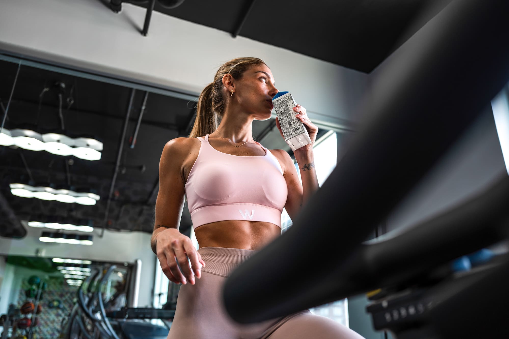 Woman in activewear hydrating during a gym workout.