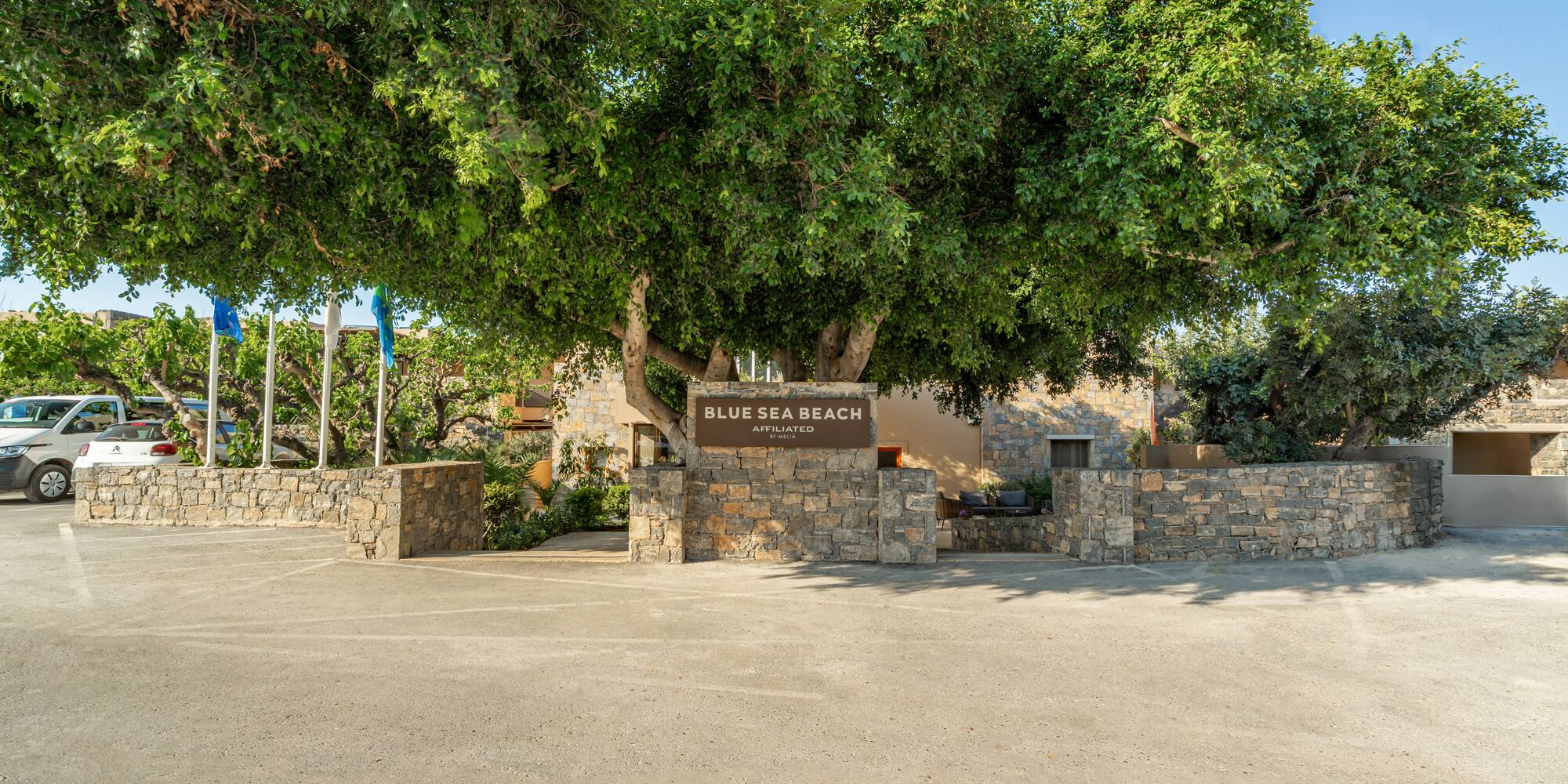 Blue Sea Beach Melia entrance sign with large tree and parking.
