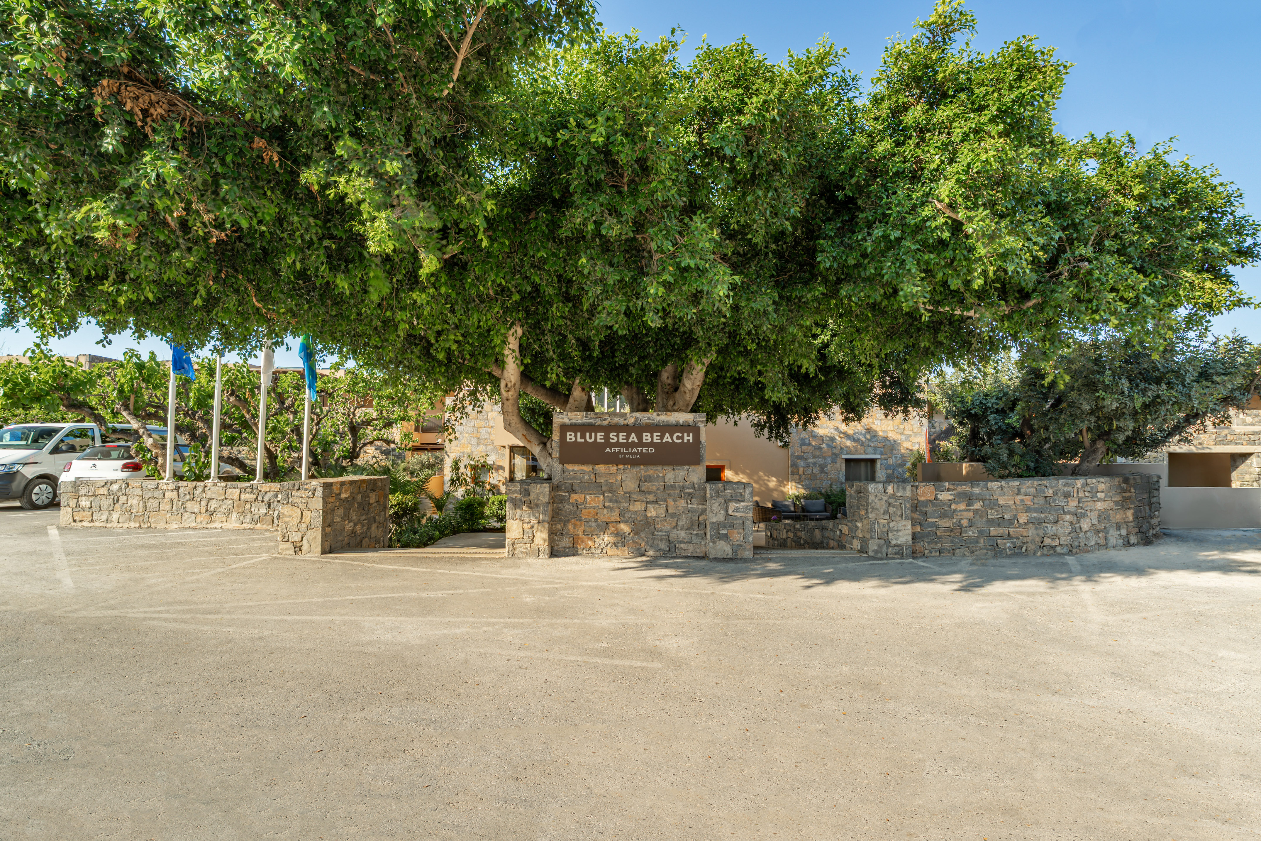 Blue Sea Beach Melia entrance sign with large tree and parking.
