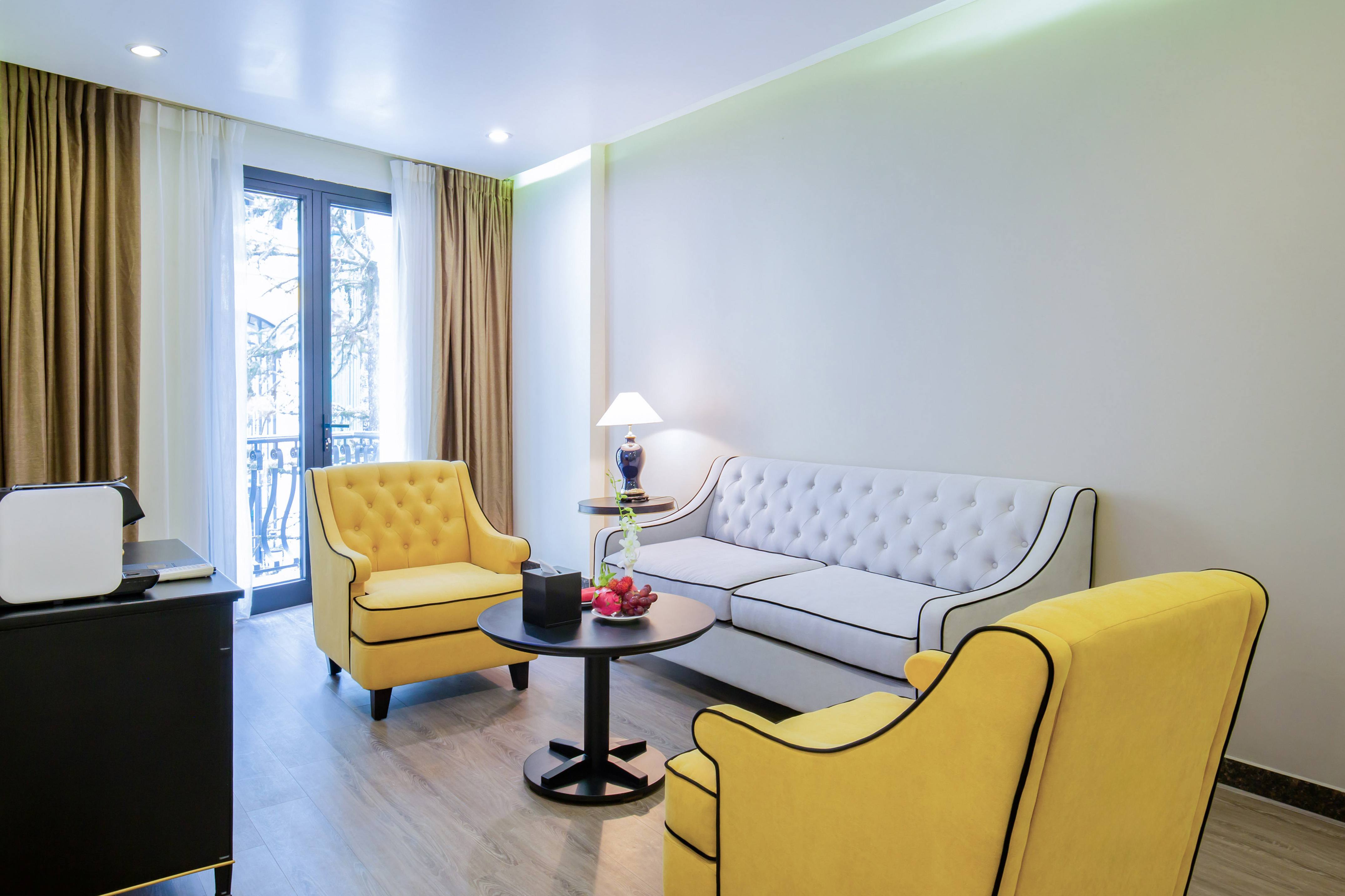 Modern hotel living room with white sofa and yellow armchairs.