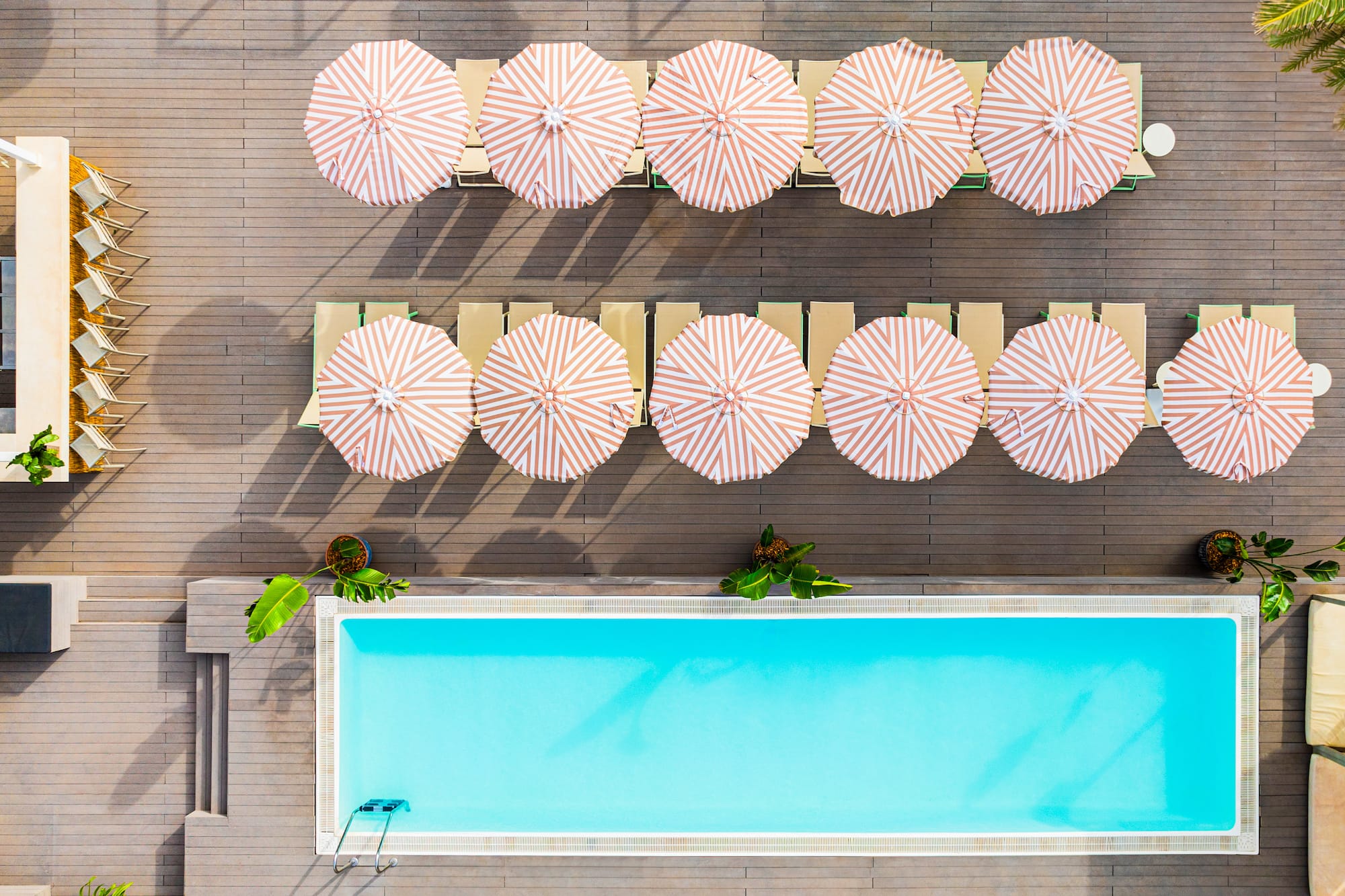 Resort pool deck: striped umbrellas, lounge chairs, and turquoise water.