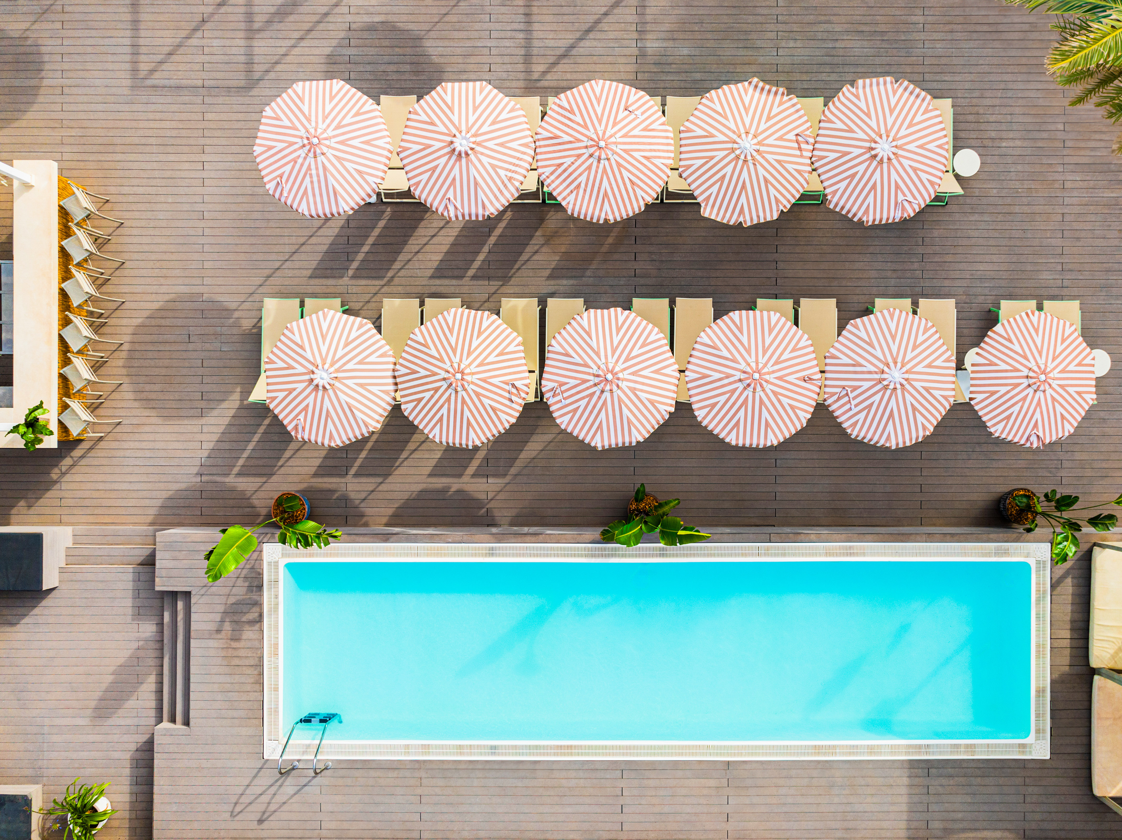 Resort pool deck: striped umbrellas, lounge chairs, and turquoise water.