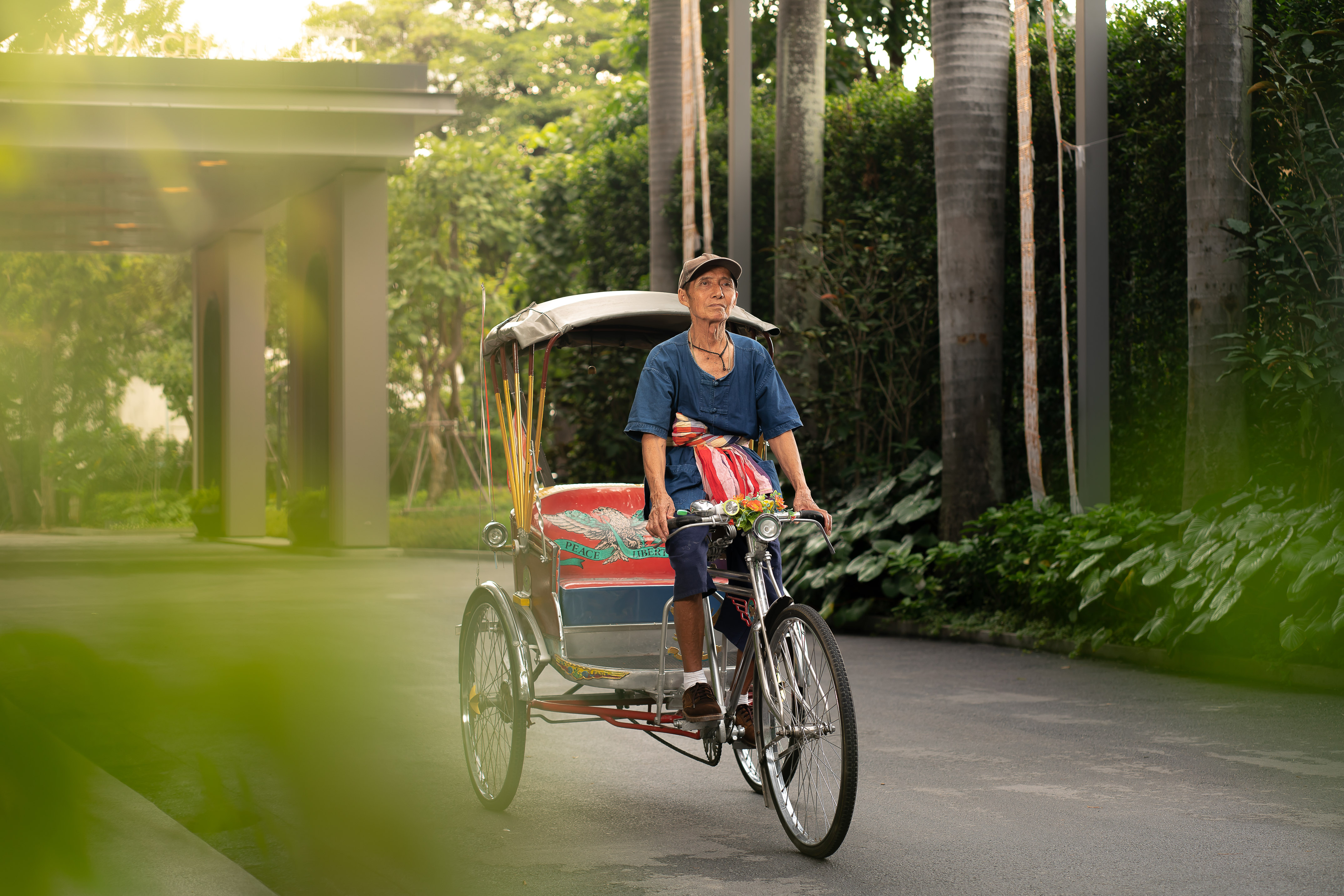 Elderly man driving a traditional Thai rickshaw at a tropical resort.