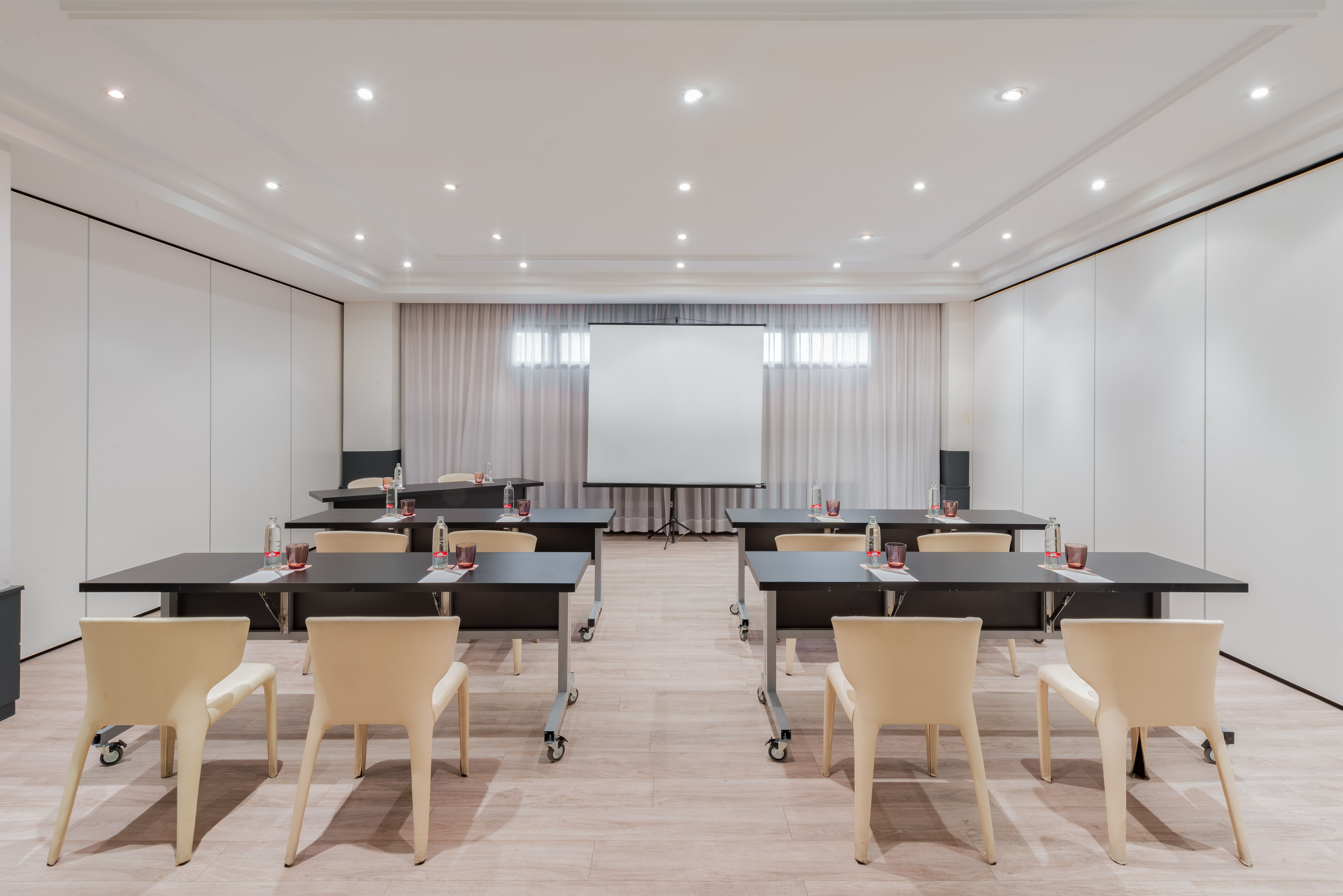Empty modern conference room setup with projection screen, tables, and chairs.