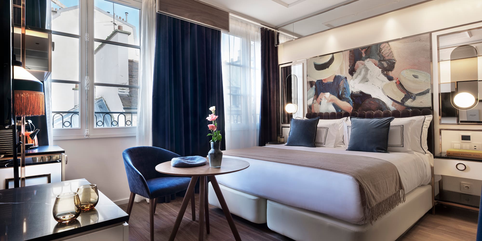 Modern luxury hotel room with abstract art, large bed, and city view window.