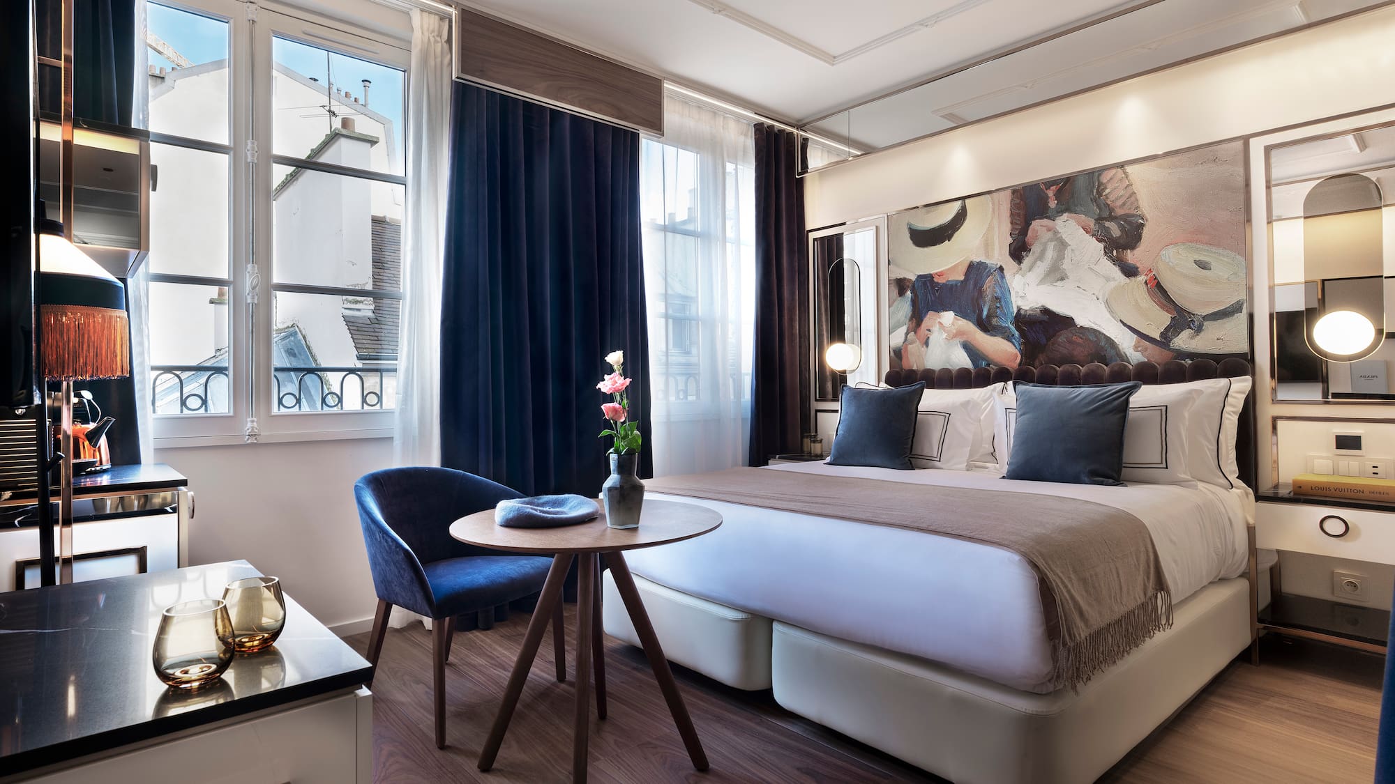 Modern luxury hotel room with abstract art, large bed, and city view window.