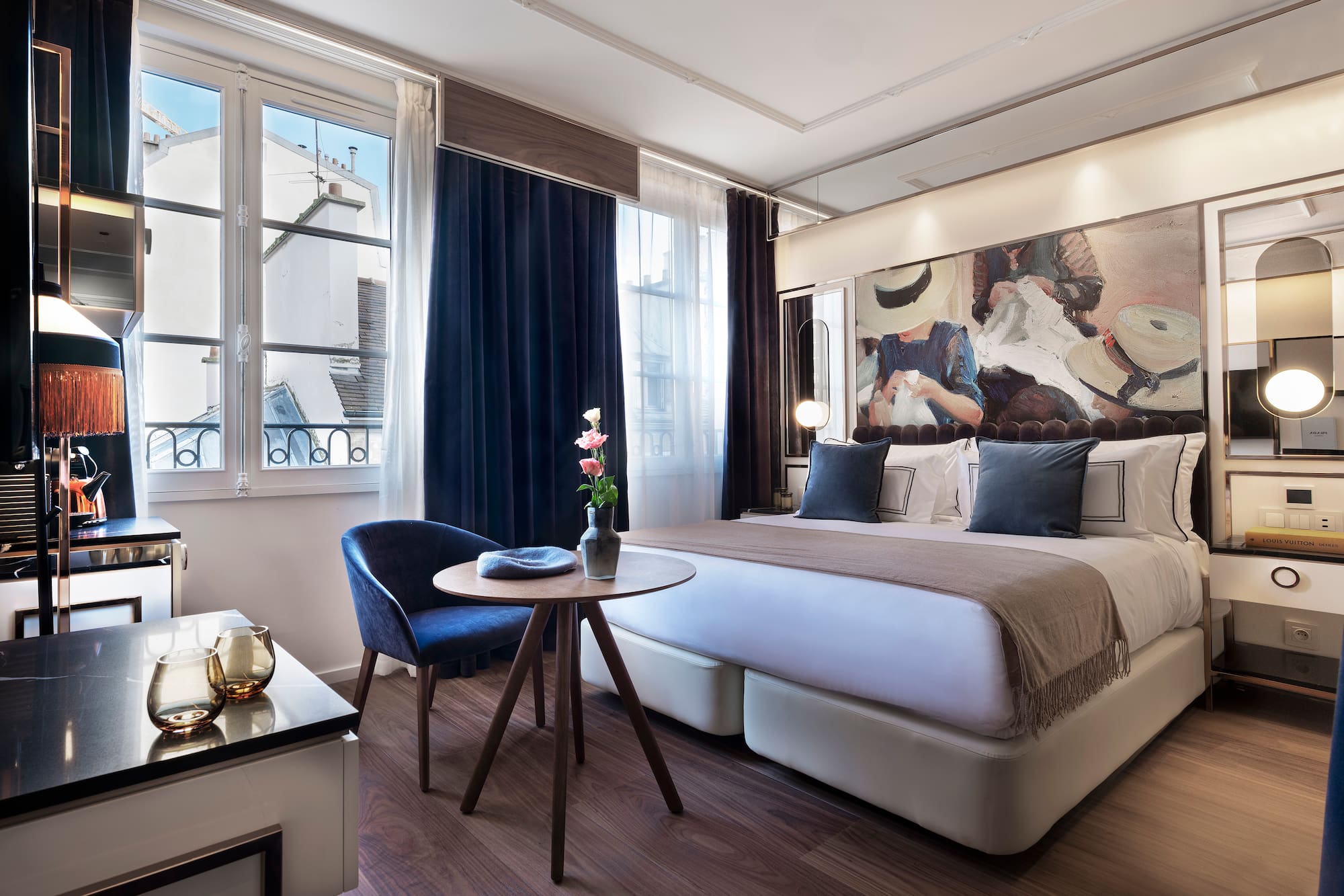 Modern luxury hotel room with abstract art, large bed, and city view window.