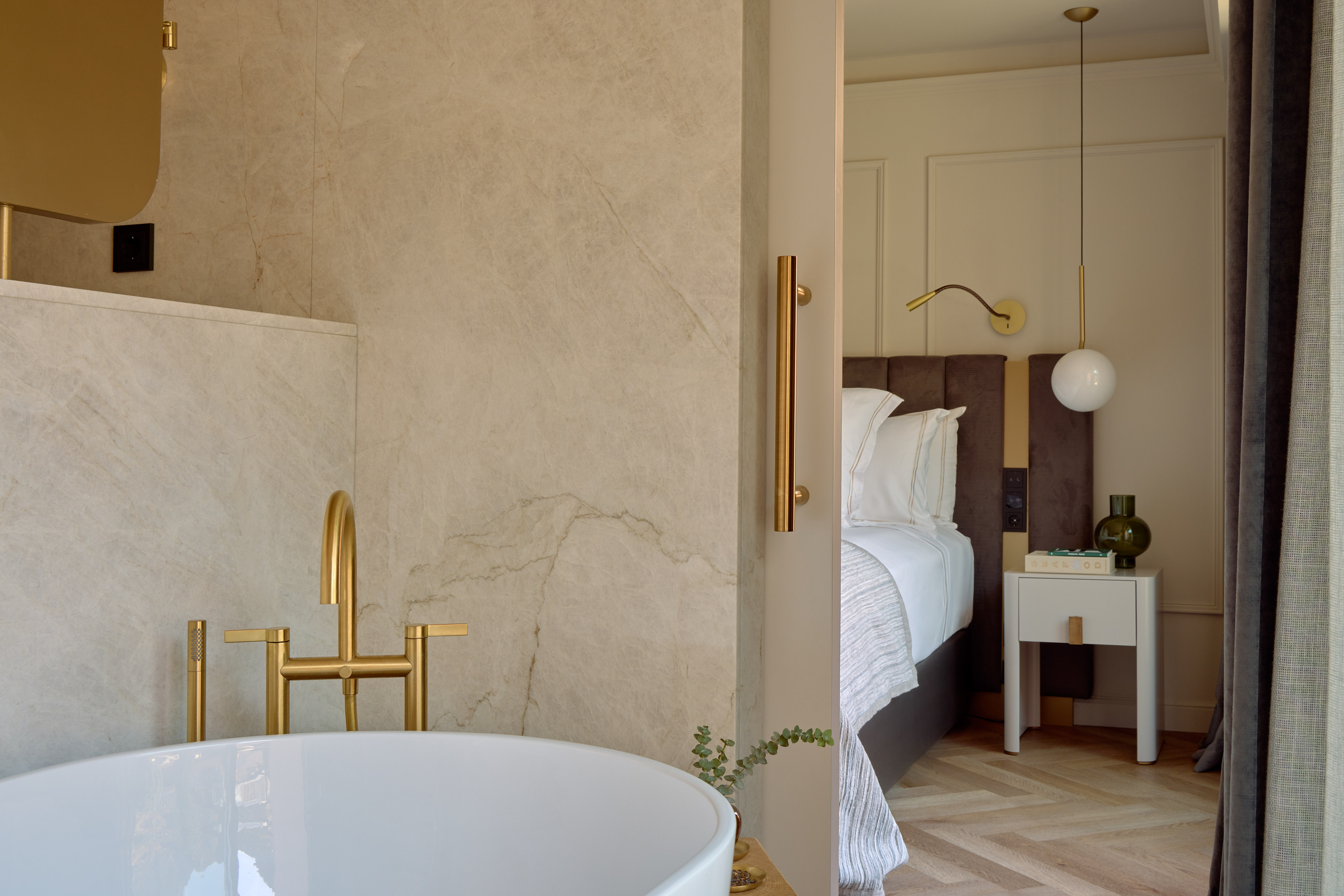 Modern luxury hotel suite with open bathroom and gold fixtures.