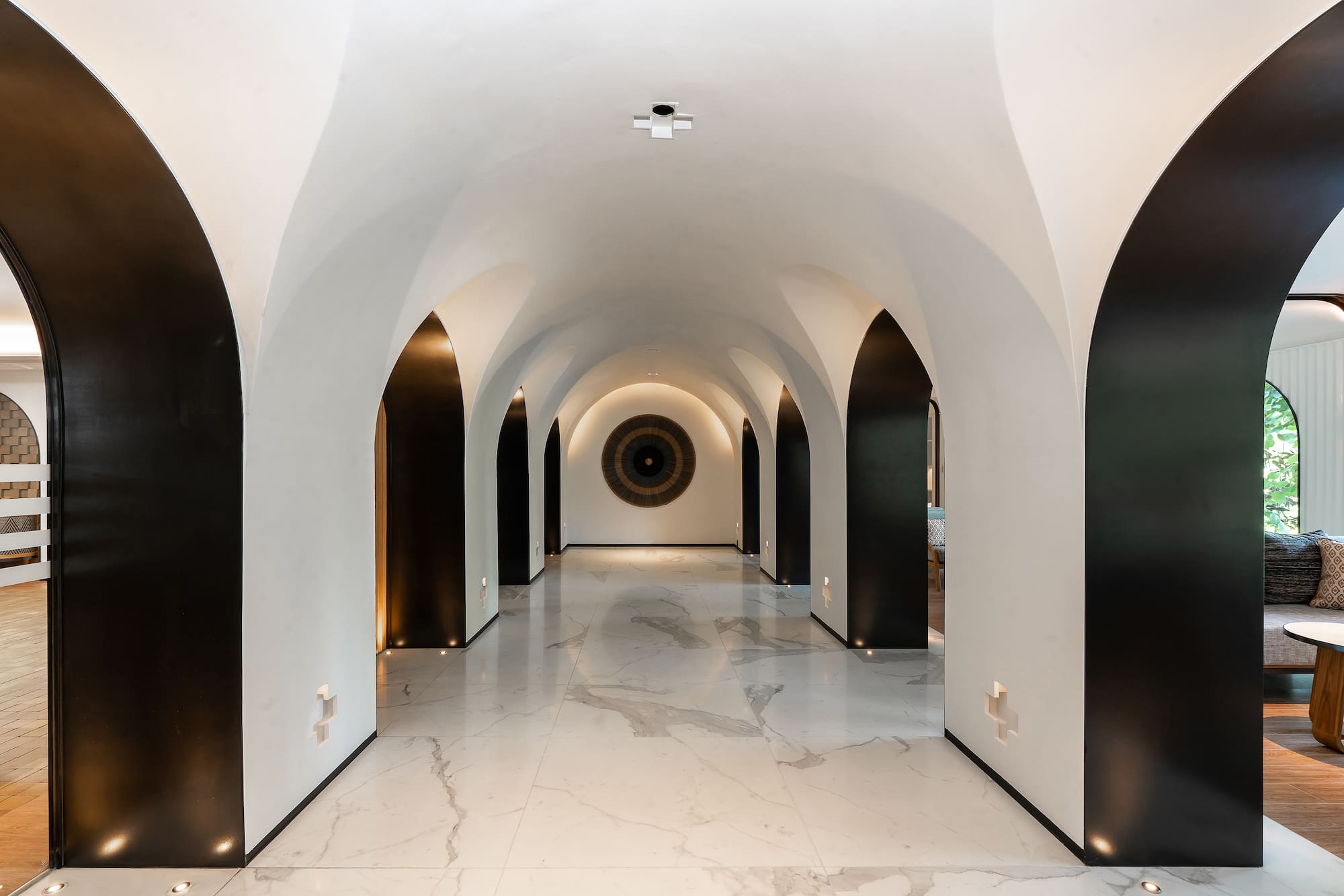 Luxury vaulted hallway with black arches, white walls, and marble flooring.