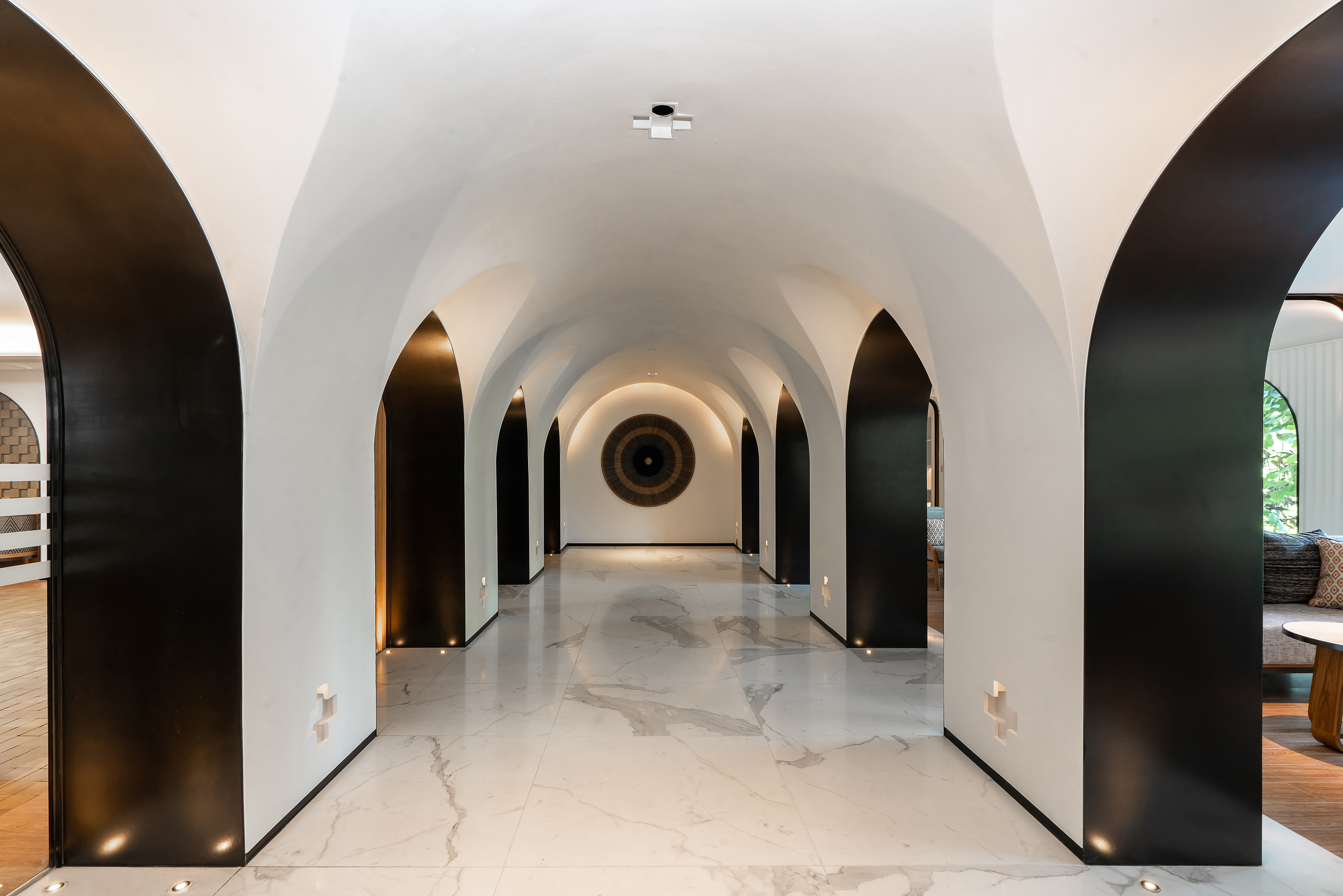 Luxury vaulted hallway with black arches, white walls, and marble flooring.