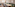 Interior de restaurante moderno con asientos verdes de terciopelo y mesas blancas.