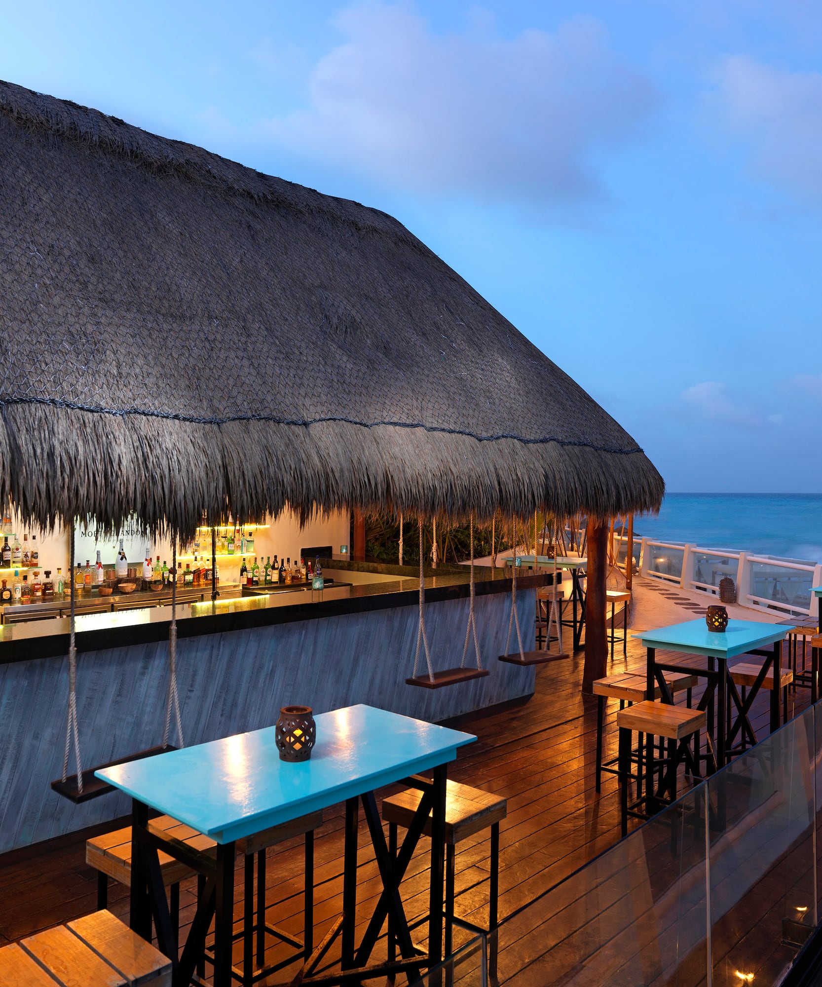 a bar with tables and chairs on a deck overlooking the ocean
