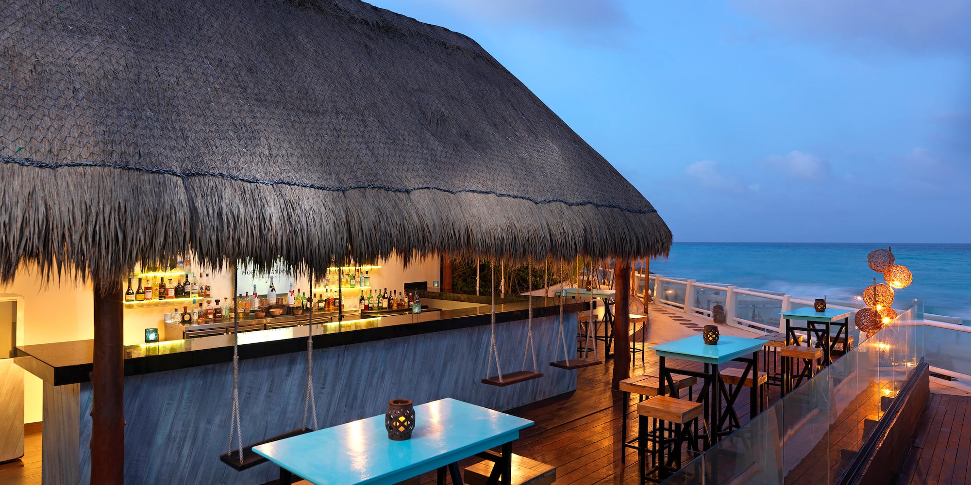 a bar with tables and chairs on a deck overlooking the ocean