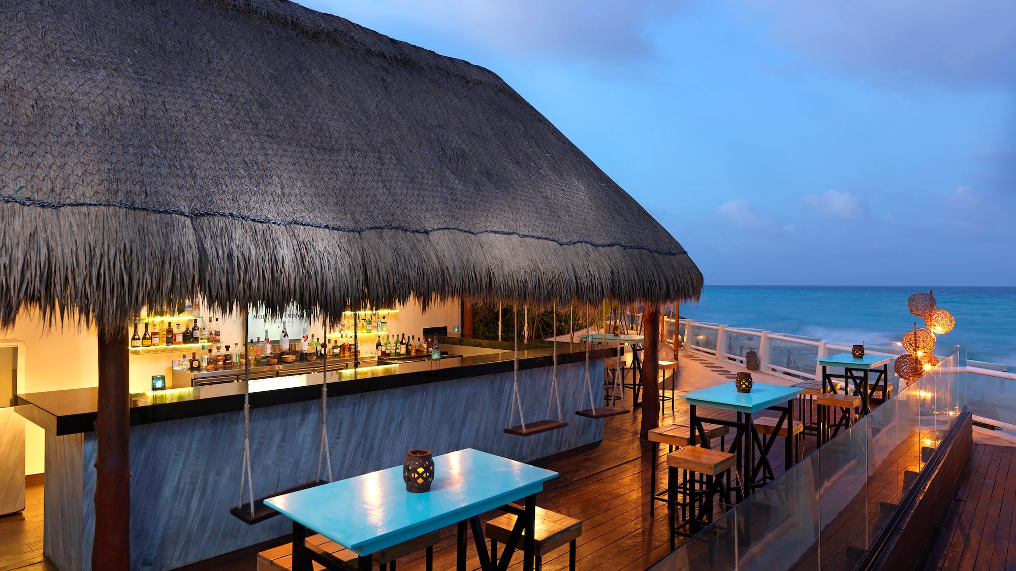 a bar with tables and chairs on a deck overlooking the ocean