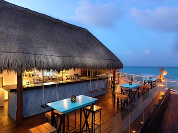 a bar with tables and chairs on a deck overlooking the ocean