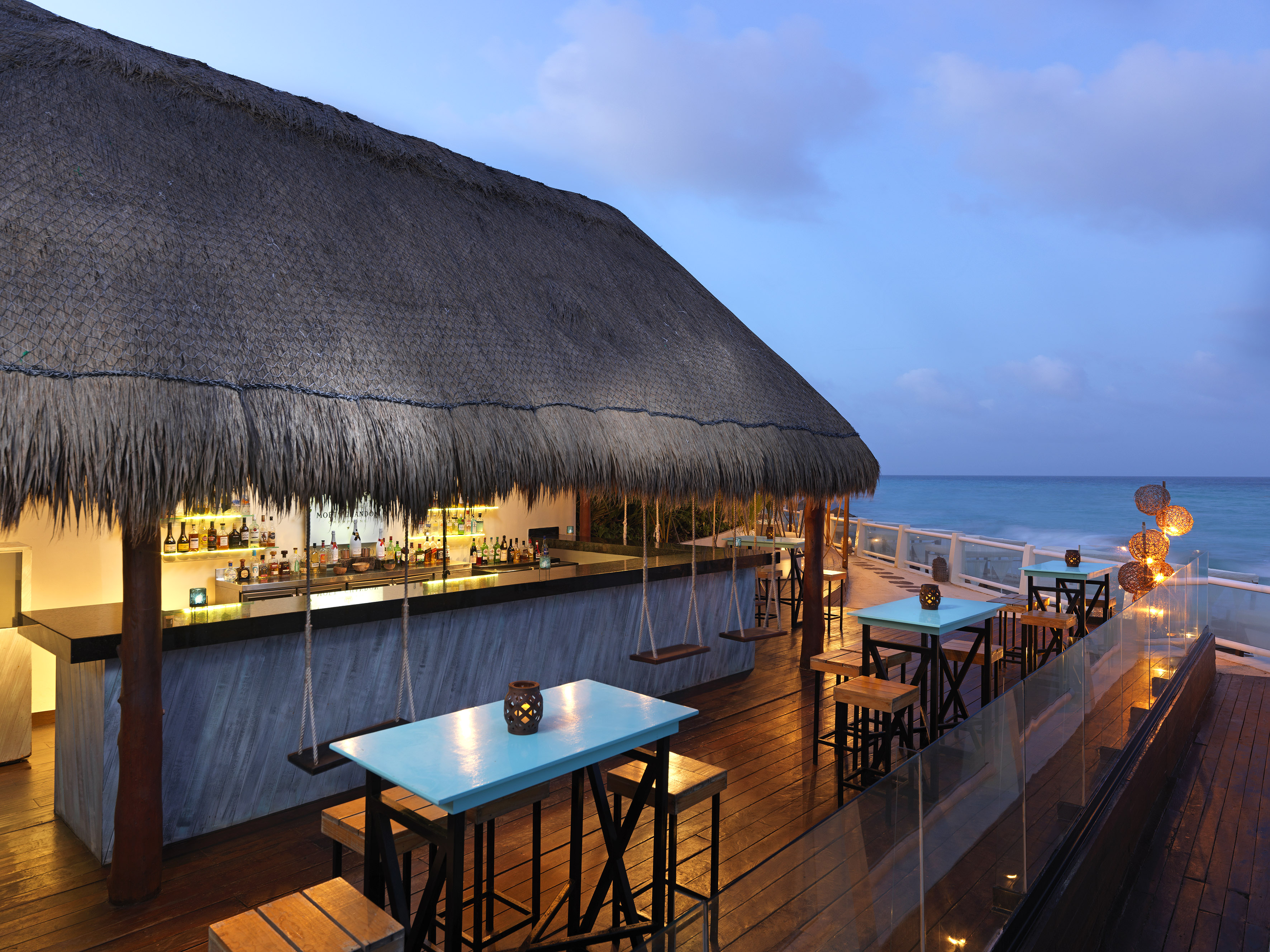 a bar with tables and chairs on a deck overlooking the ocean