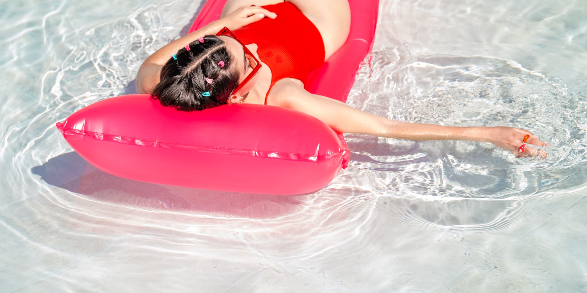 a woman lying on a pink float in a pool