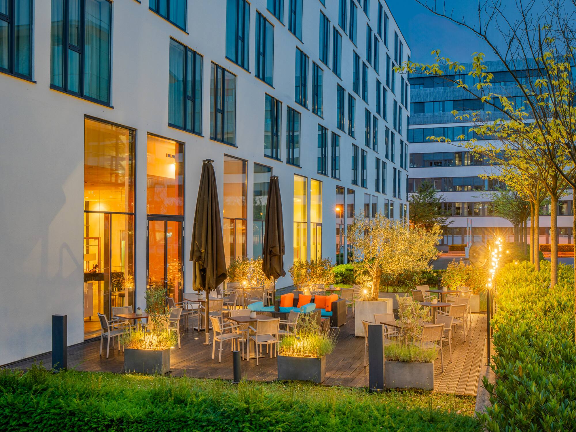 Modern hotel patio with outdoor seating, illuminated by warm evening lights.