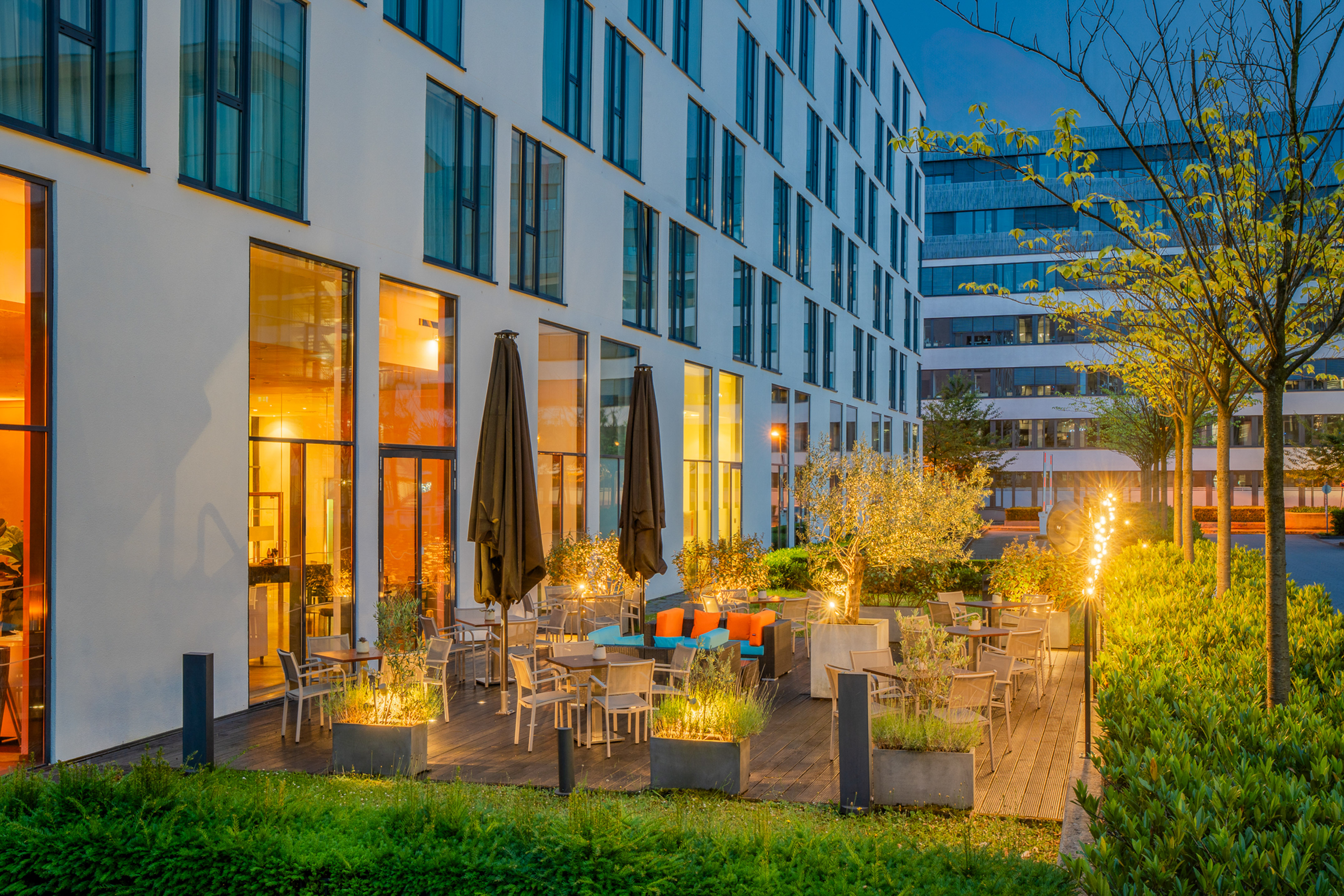 Modern hotel patio with outdoor seating, illuminated by warm evening lights.
