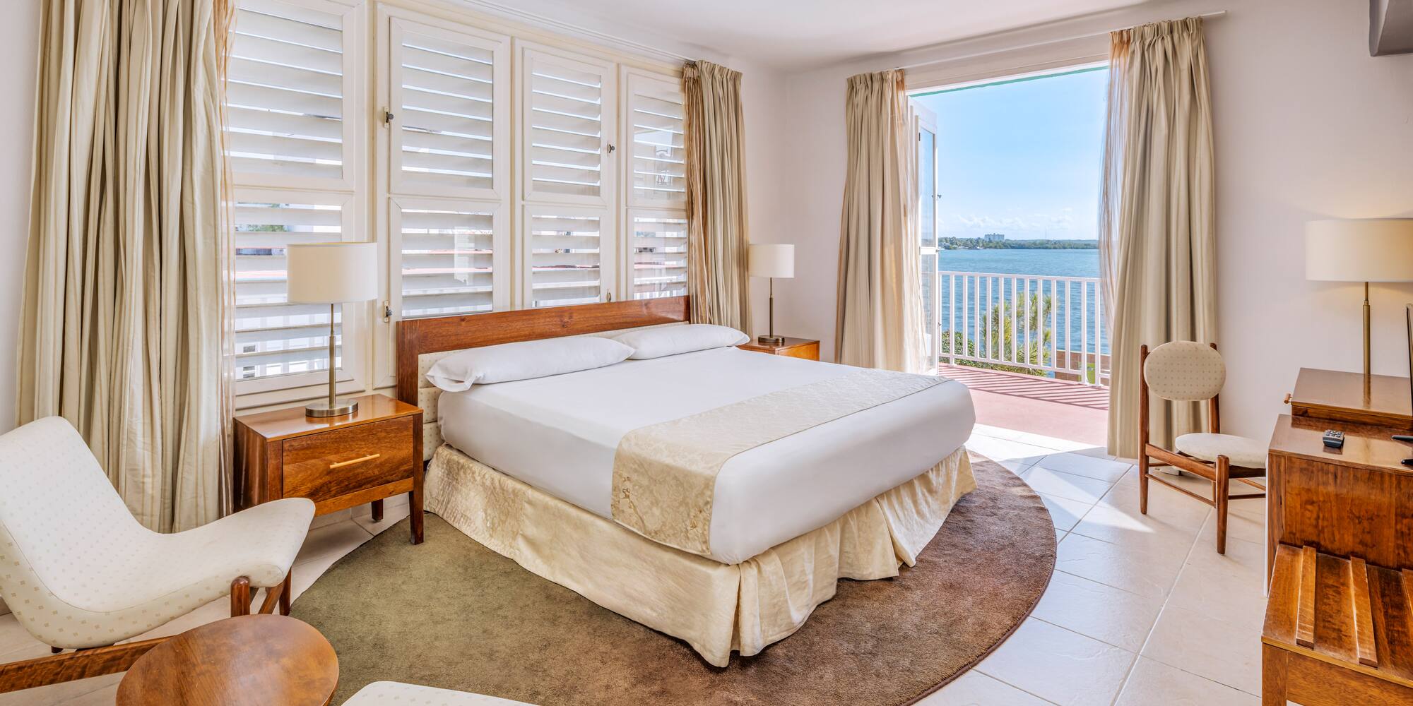 a bedroom with a large bed and chairs