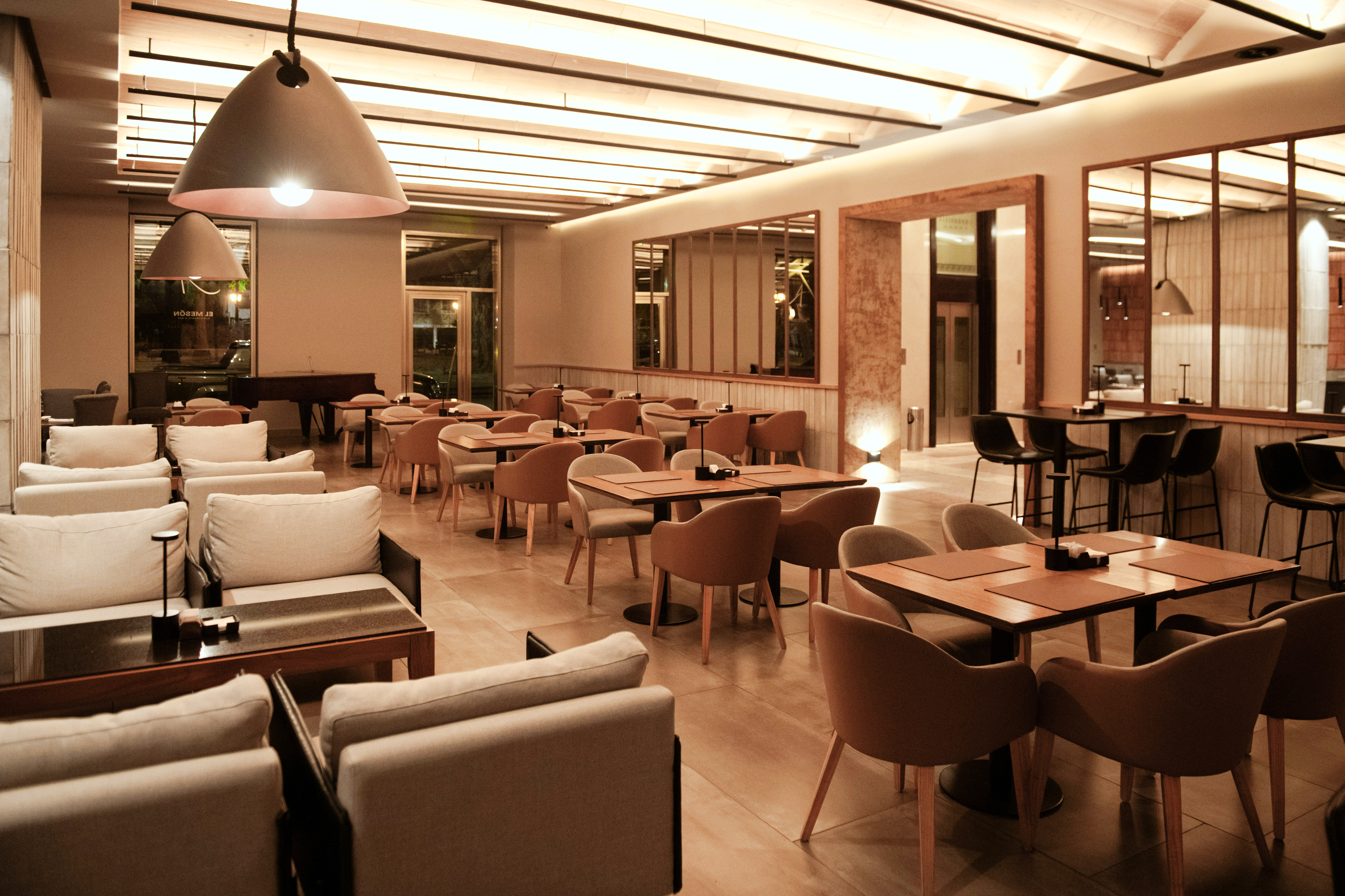Cozy restaurant dining area with modern tables, comfortable seating, warm lighting.