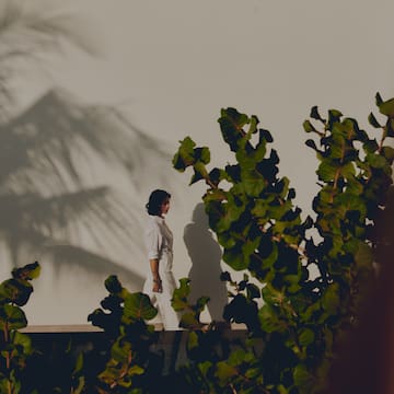 a woman standing on a ledge with leaves