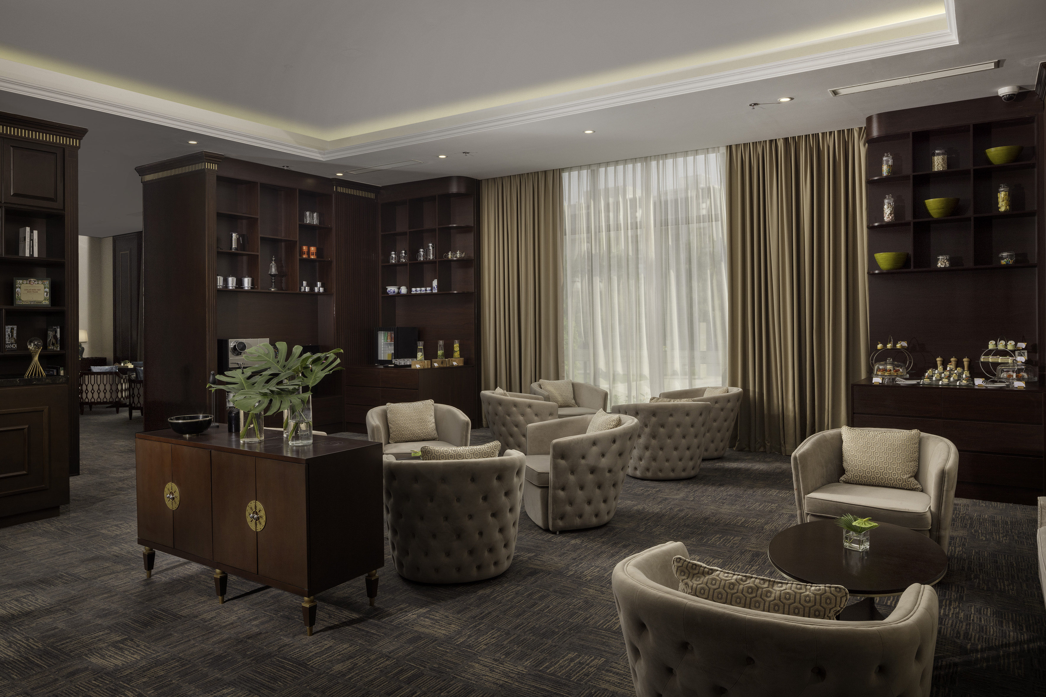 Hotel lounge with tufted armchairs, dark wood cabinetry, and natural light.