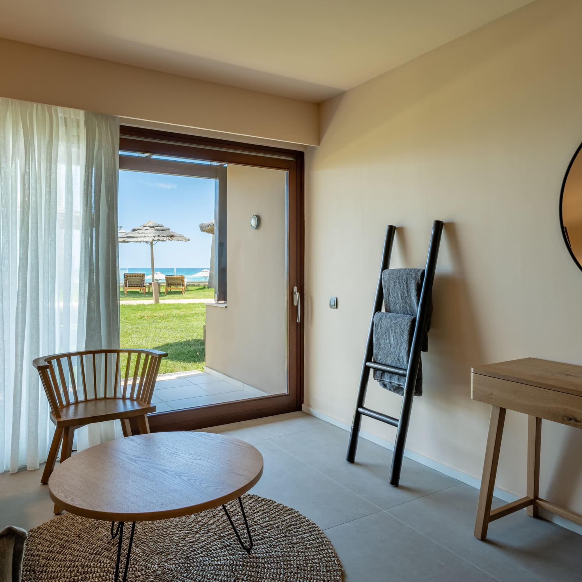 Modern hotel room with beach view patio, sofa, and contemporary decor.