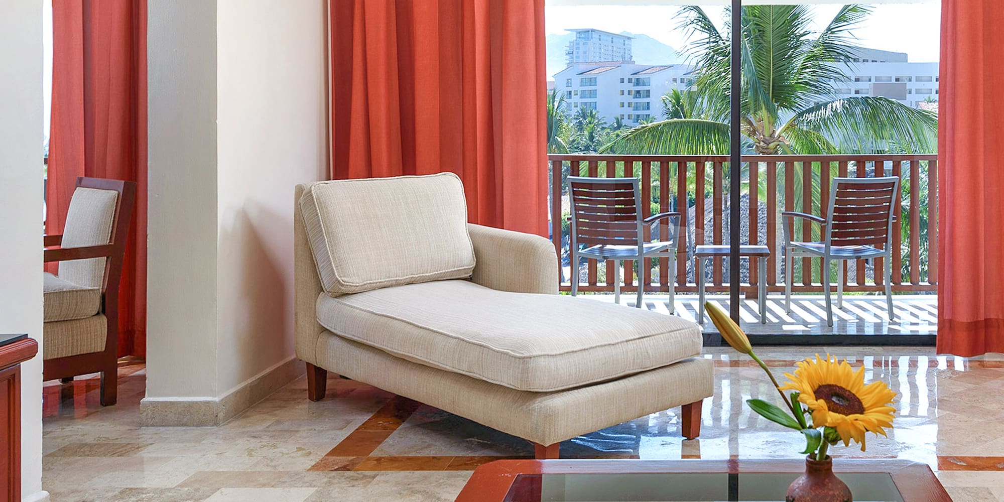 a chaise lounge in a room with a glass table and orange curtains