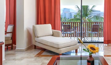 a chaise lounge in a room with a glass table and orange curtains
