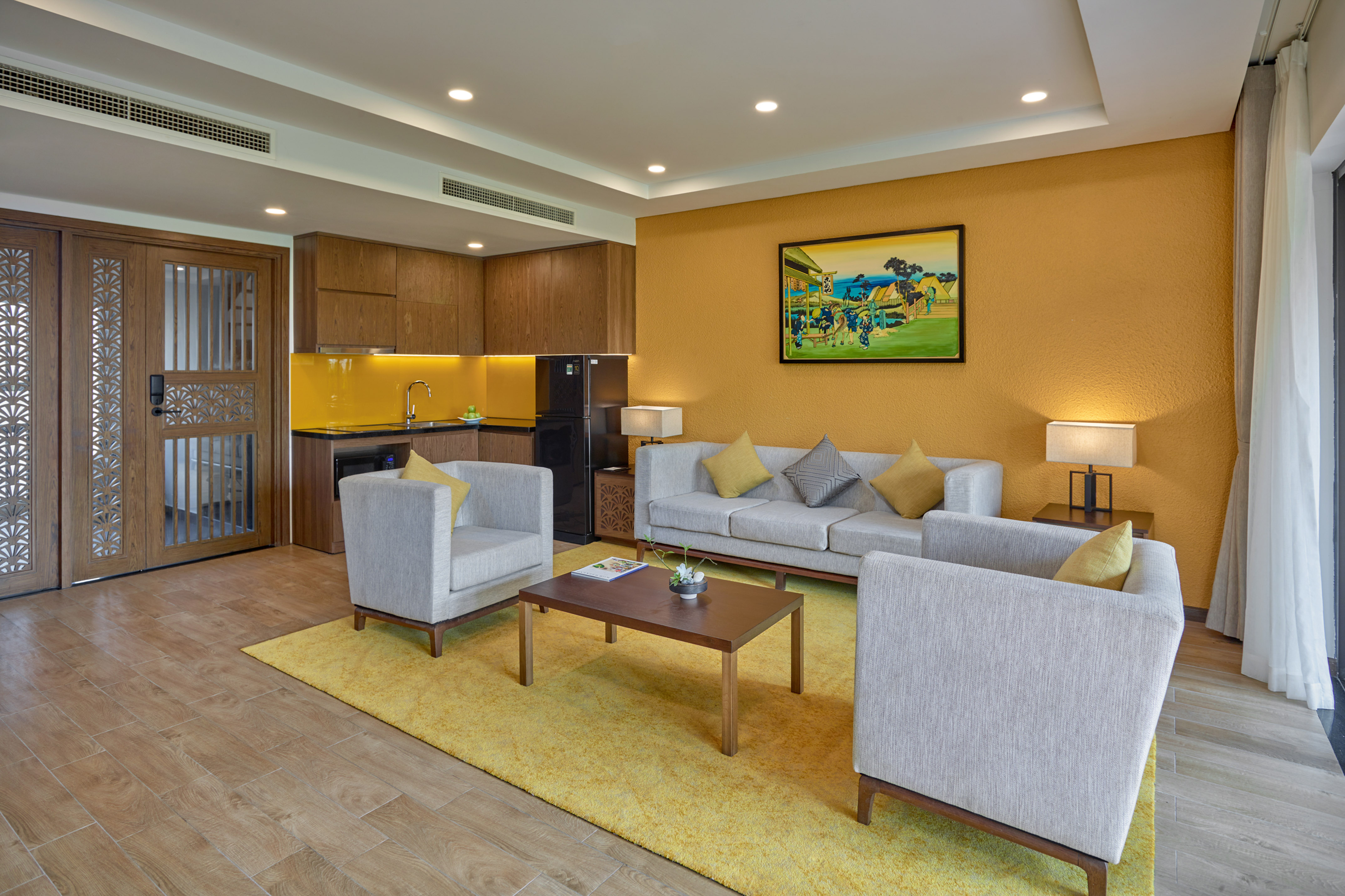 Modern suite living room and kitchen with yellow accent wall, gray sofas.