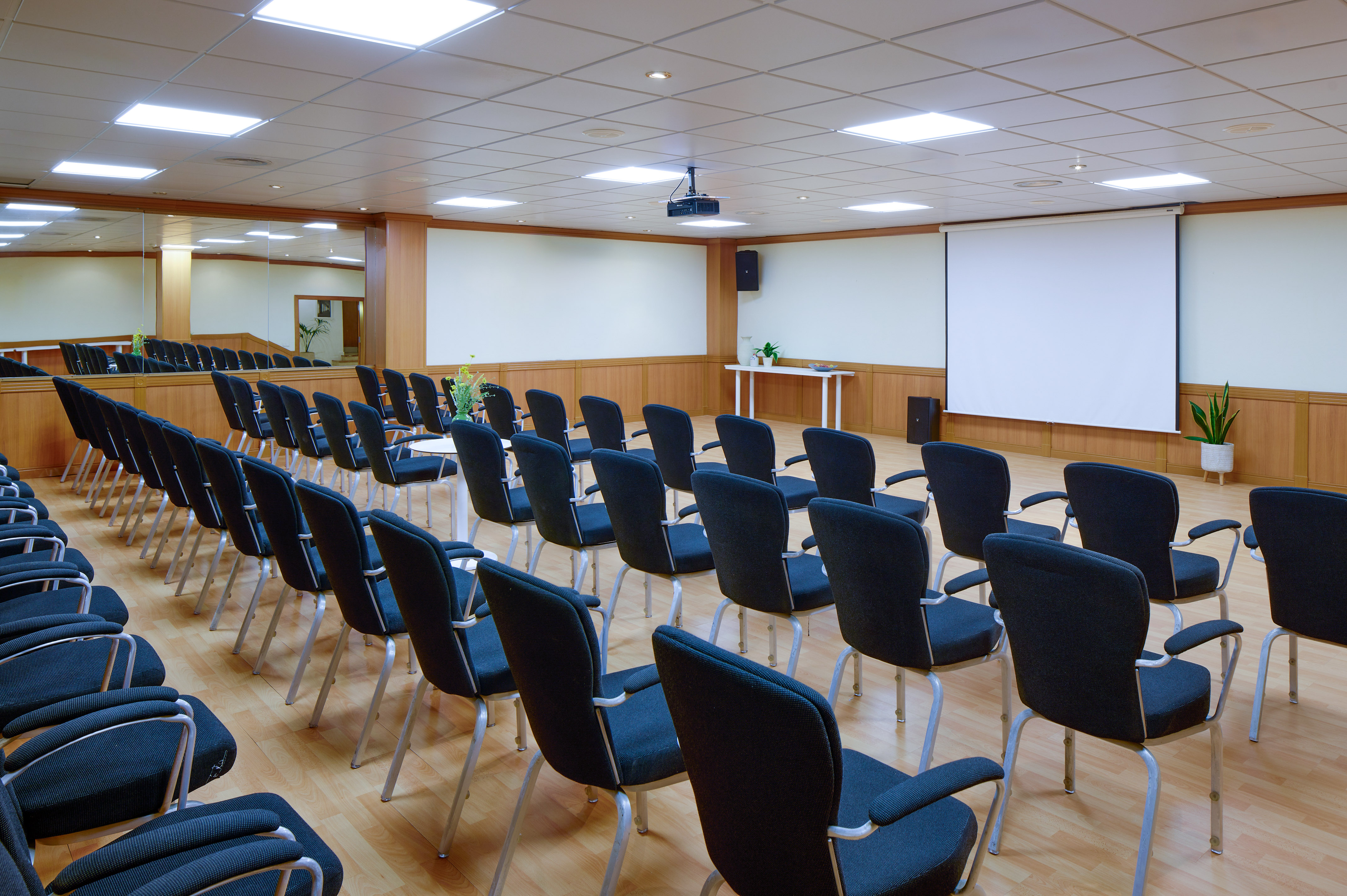 Conference room with black chairs, projector, and white screen.