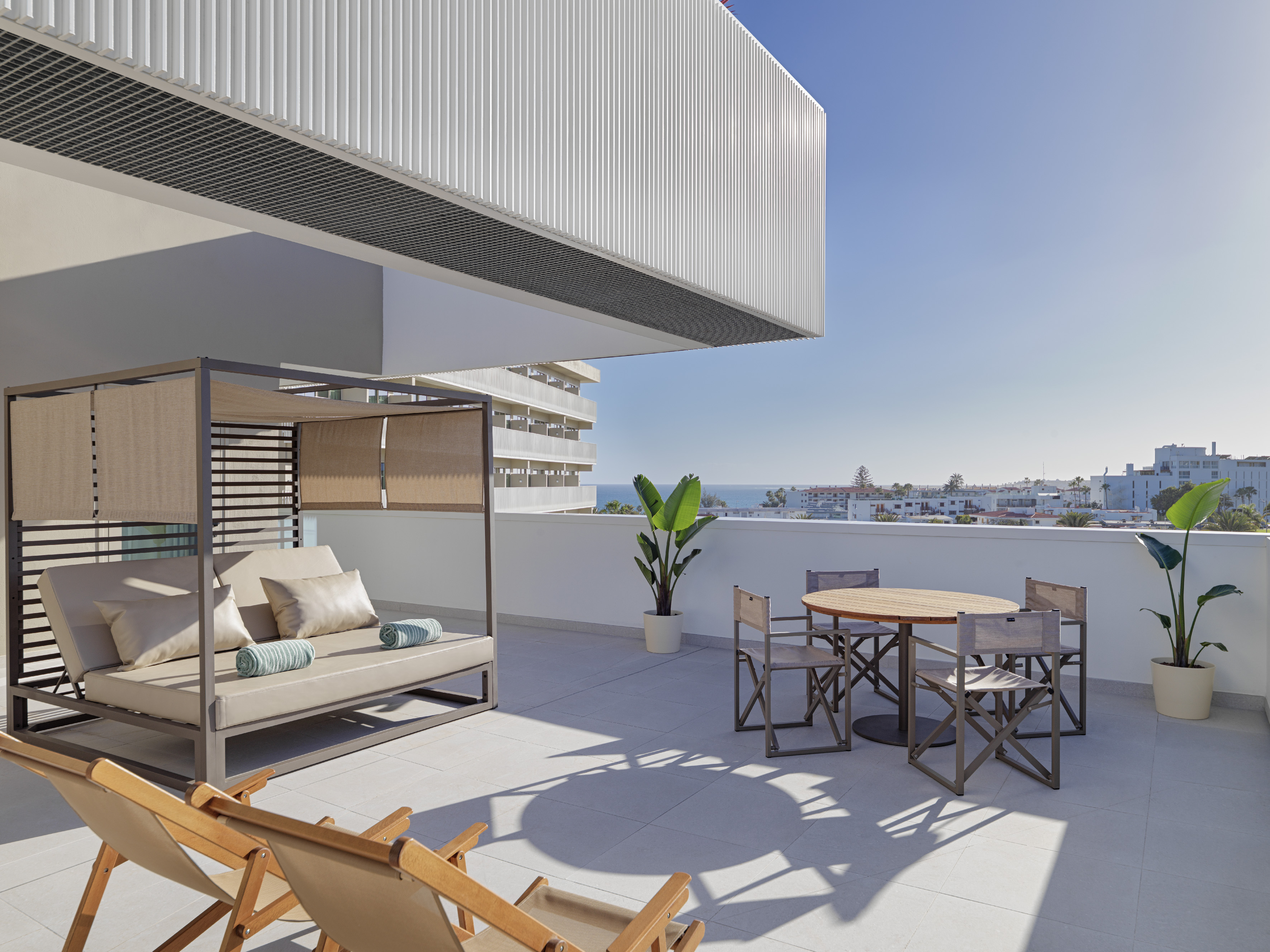 Luxury hotel terrace with ocean view, modern daybed, and outdoor furniture.